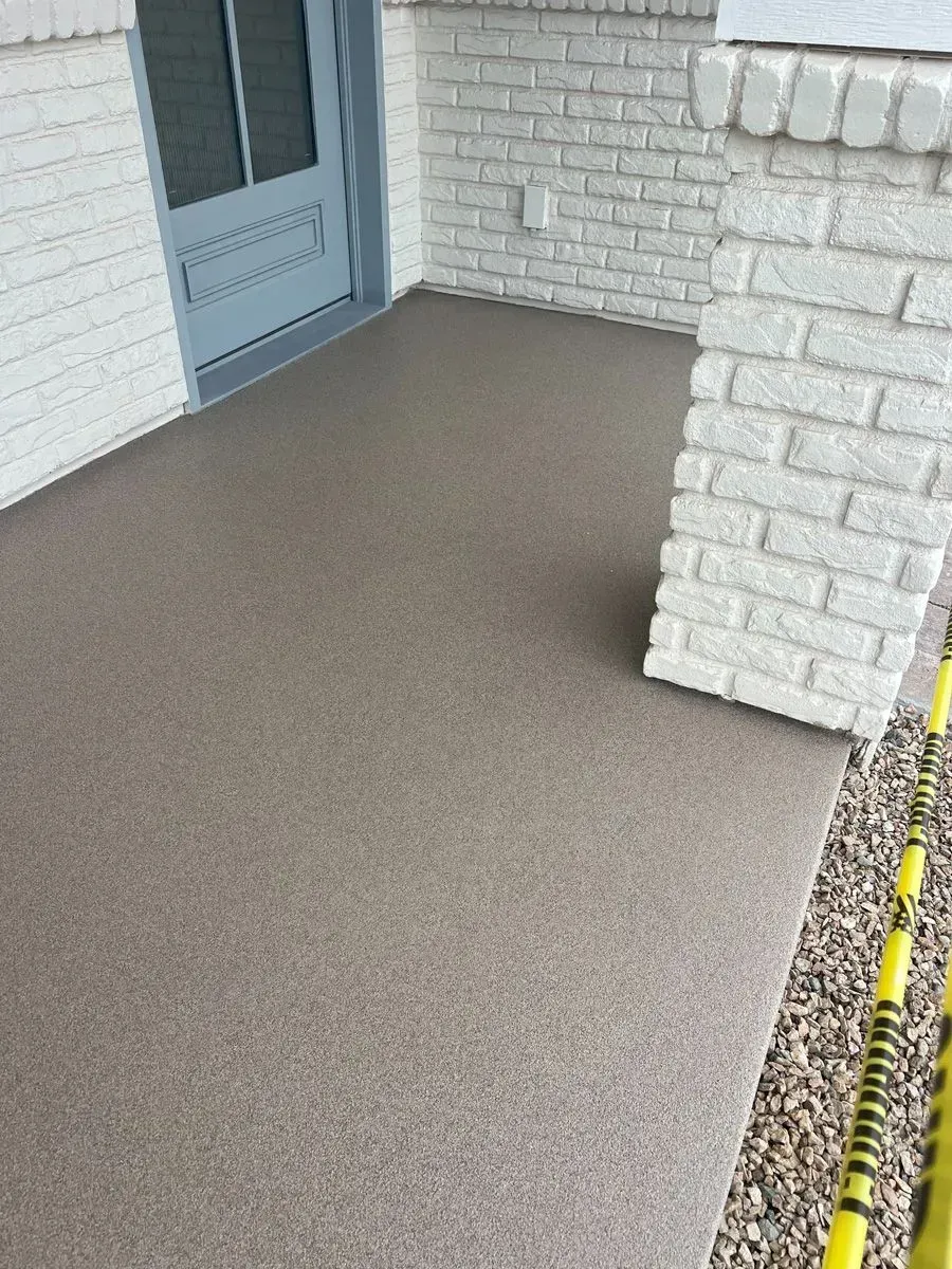 Front porch with a textured brown surface, white brick pillar, and gray door.