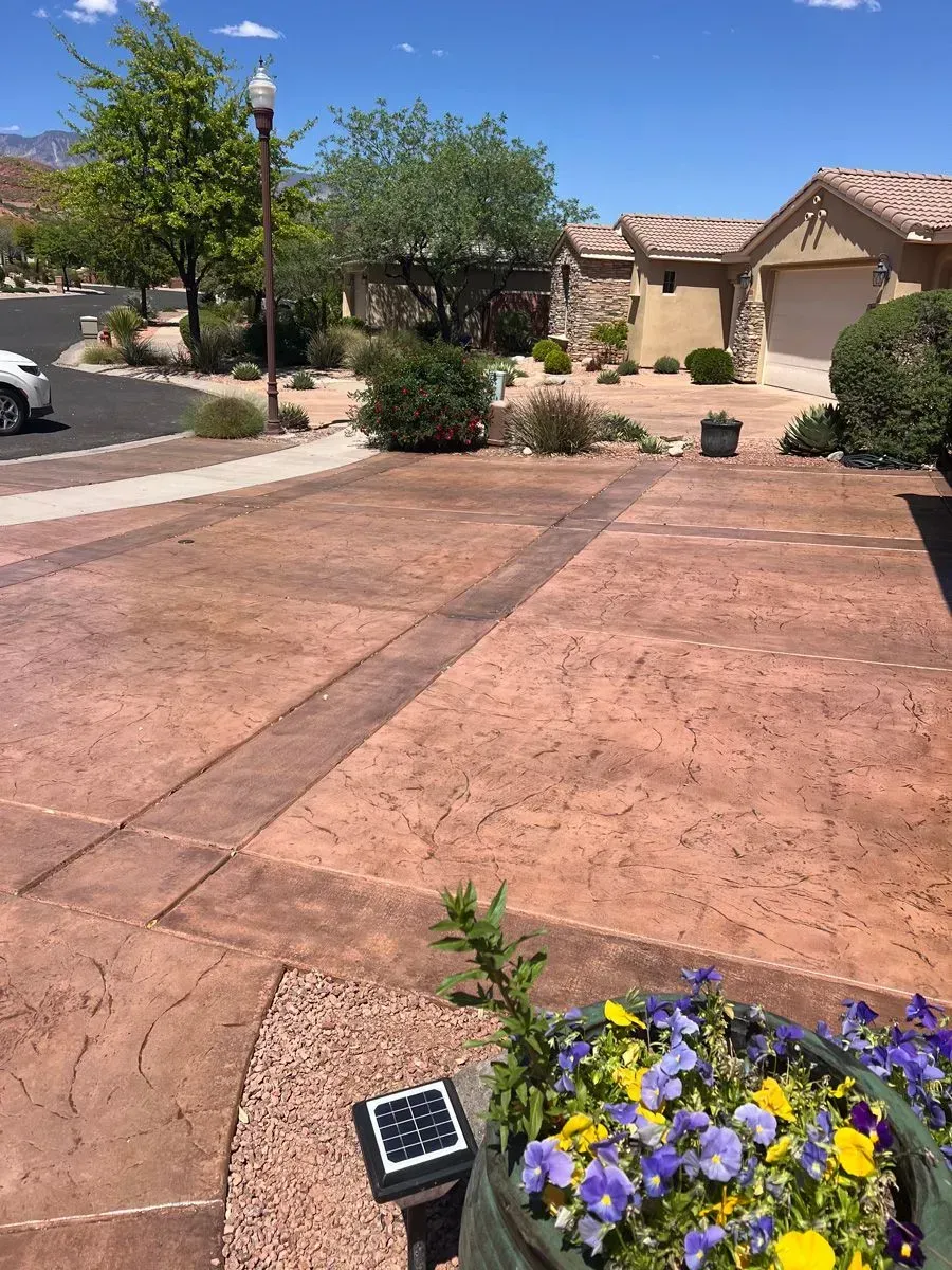 Driveway of a house with decorative concrete and landscaping, sunny day.