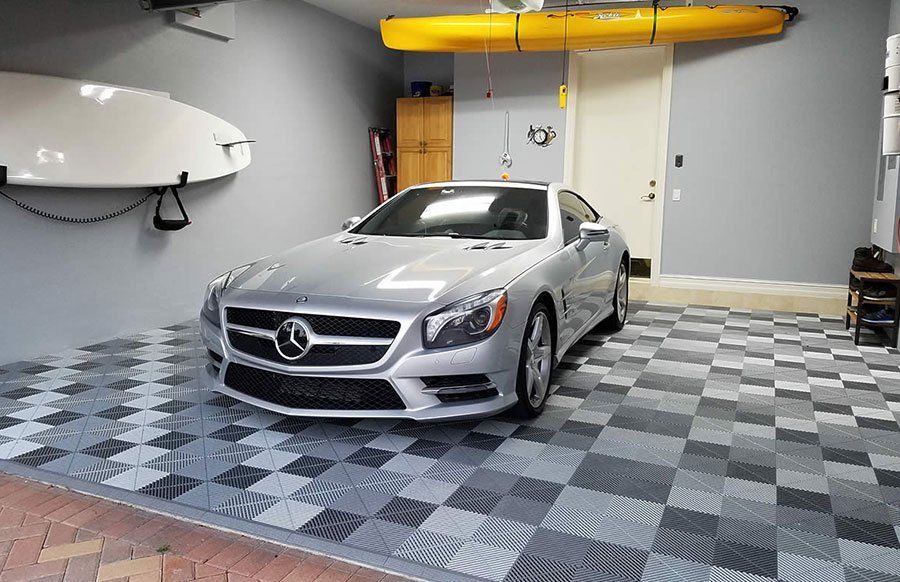 A silver mercedes slr is parked in a garage with a checkered floor.