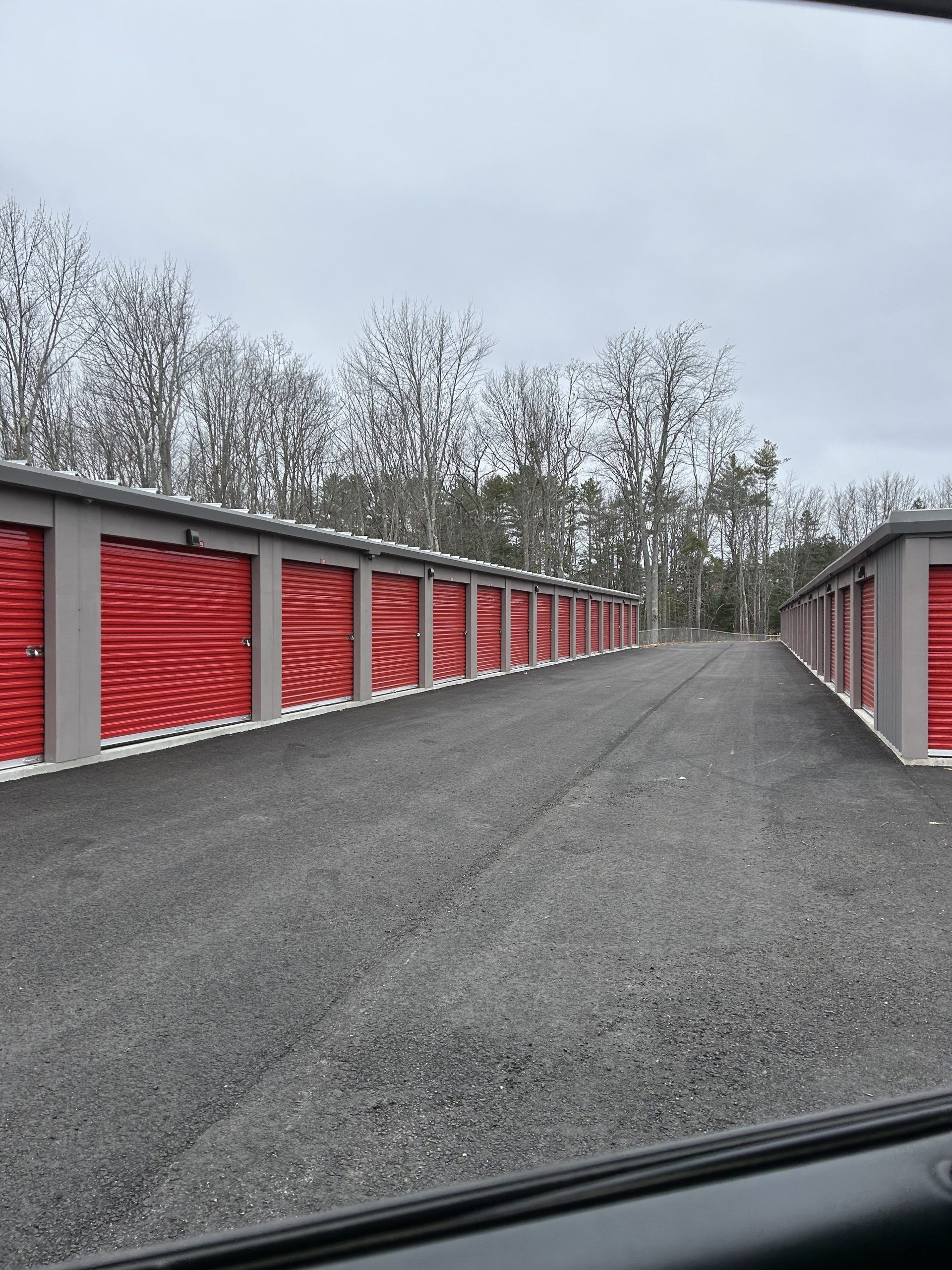 A row of red storage units are lined up on the side of a road.