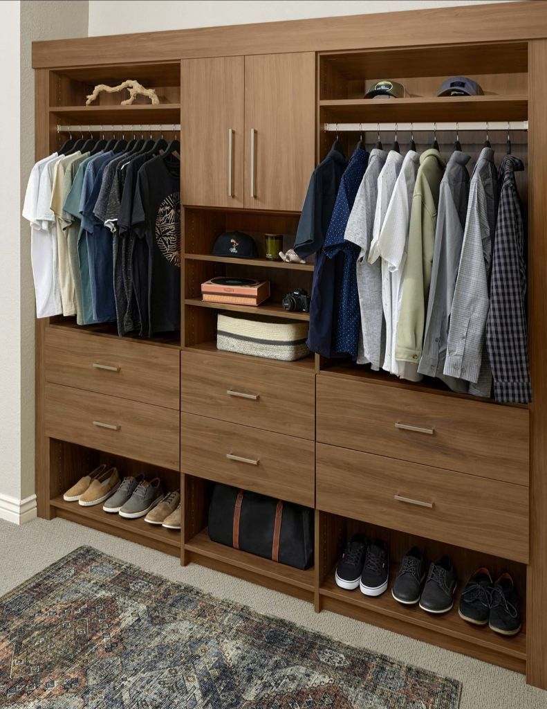 Closet organizer with hanging clothes, drawers, and shoe storage in a room.