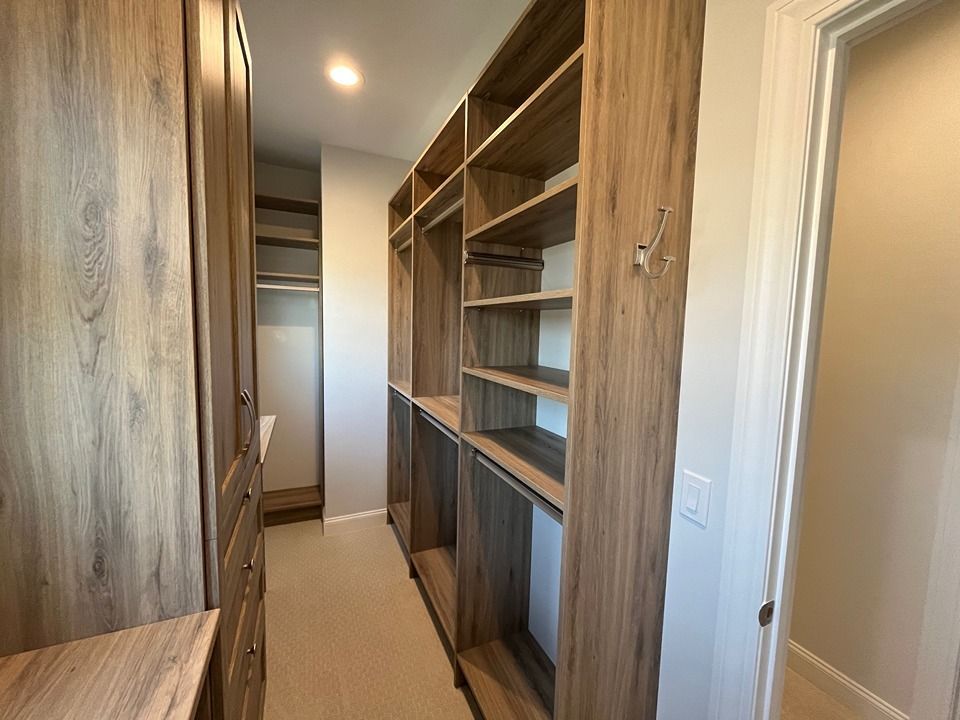 A walk in closet with wooden shelves and cabinets in a house.