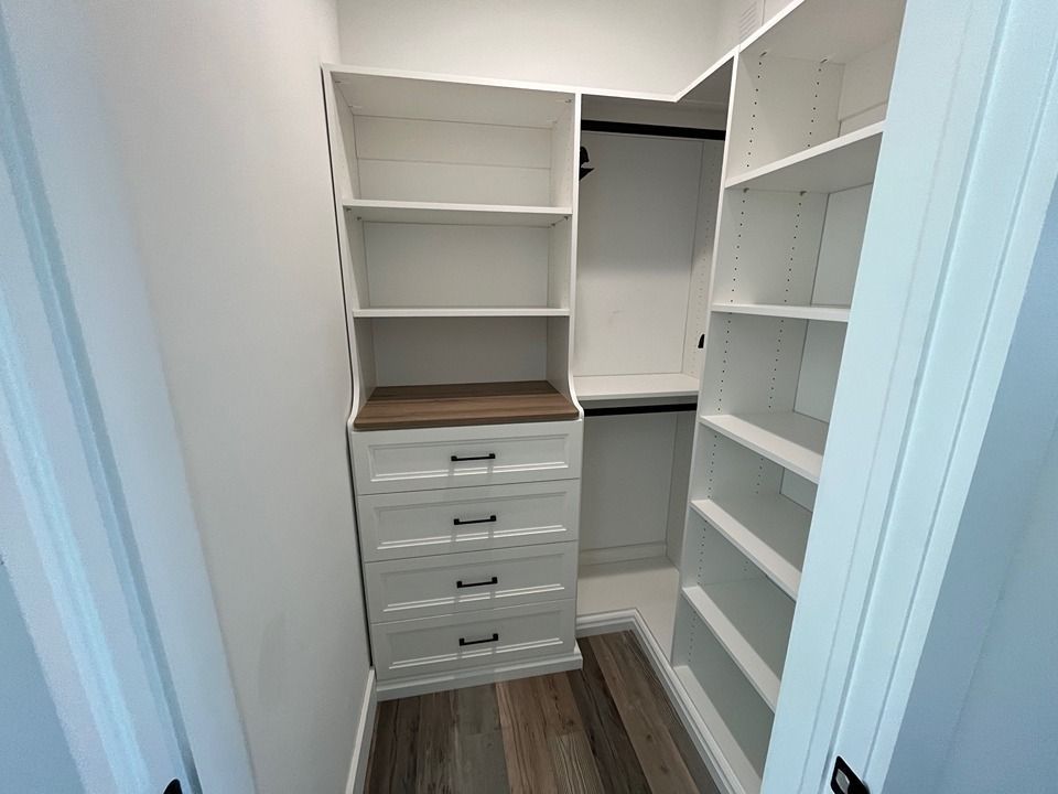 A walk in closet with lots of shelves and drawers.
