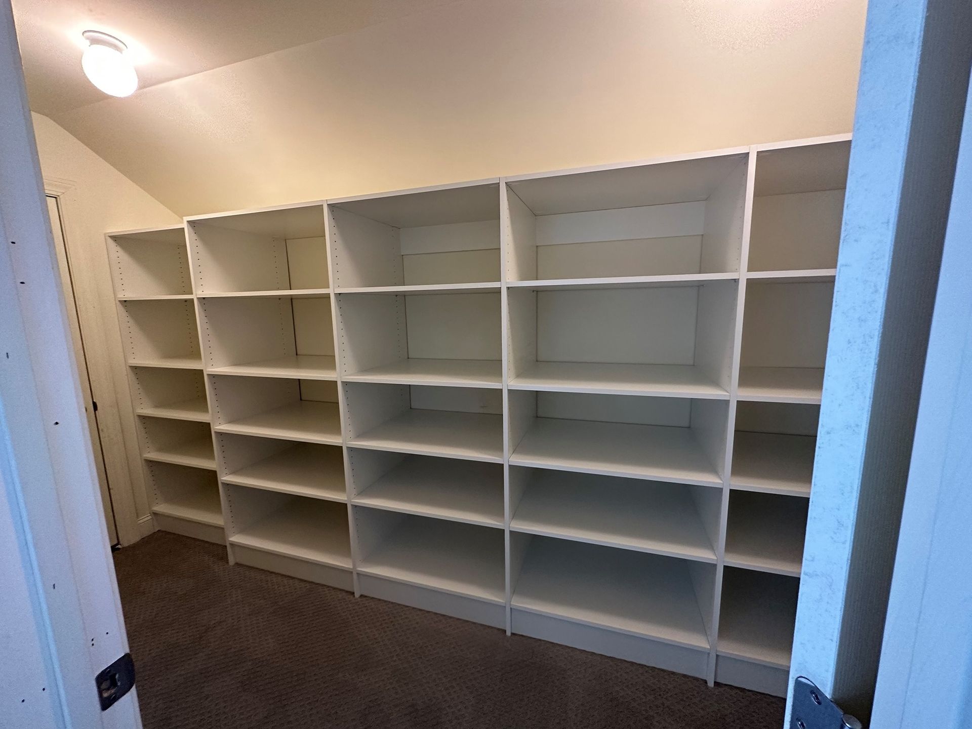 A walk in closet with lots of shelves and a door.
