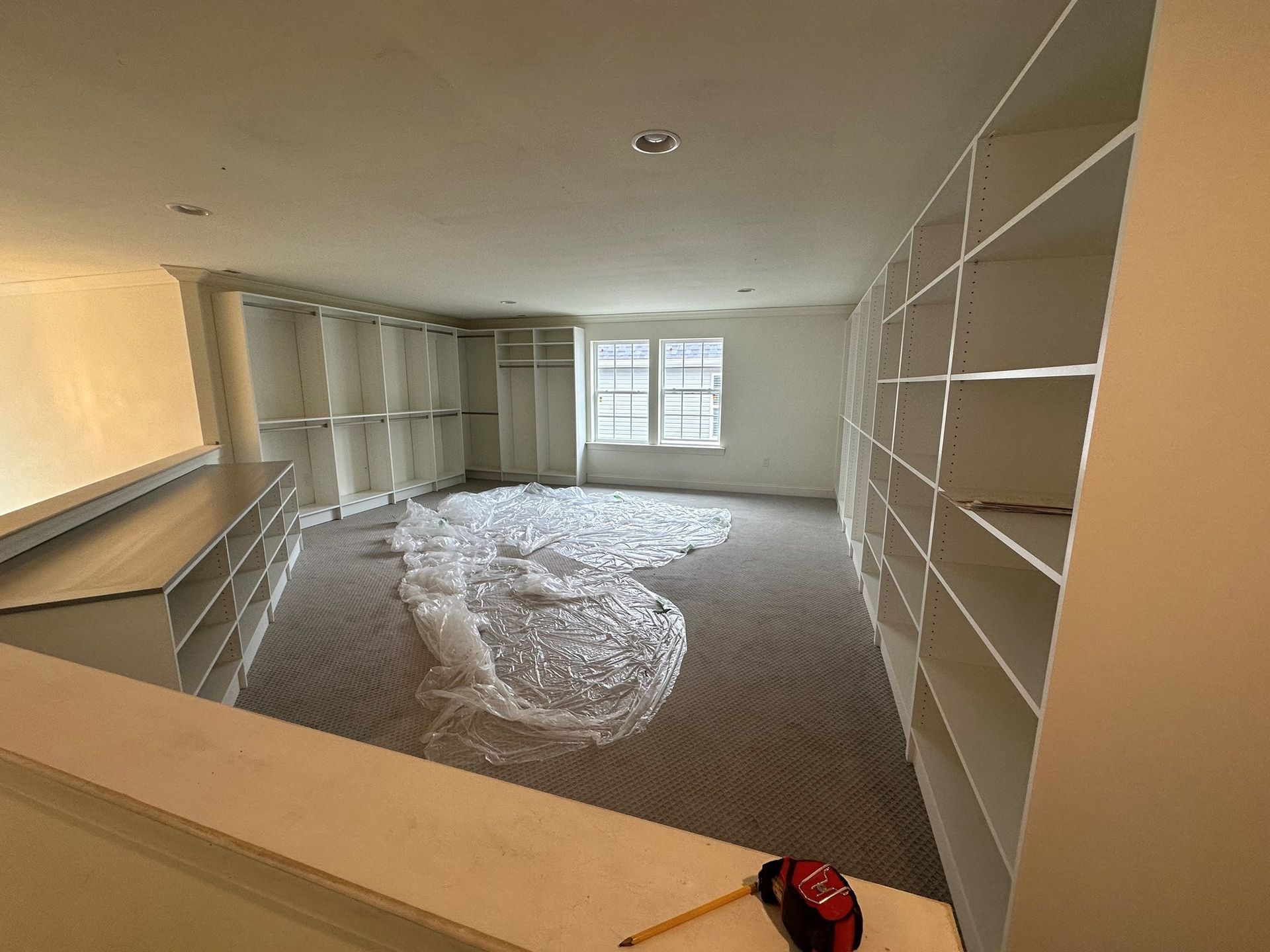 A room with a lot of shelves and a tape measure on the floor.
