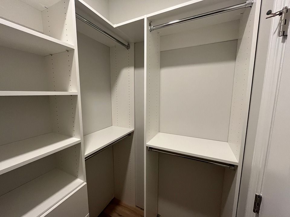 An empty walk in closet with white shelves and clothes racks.