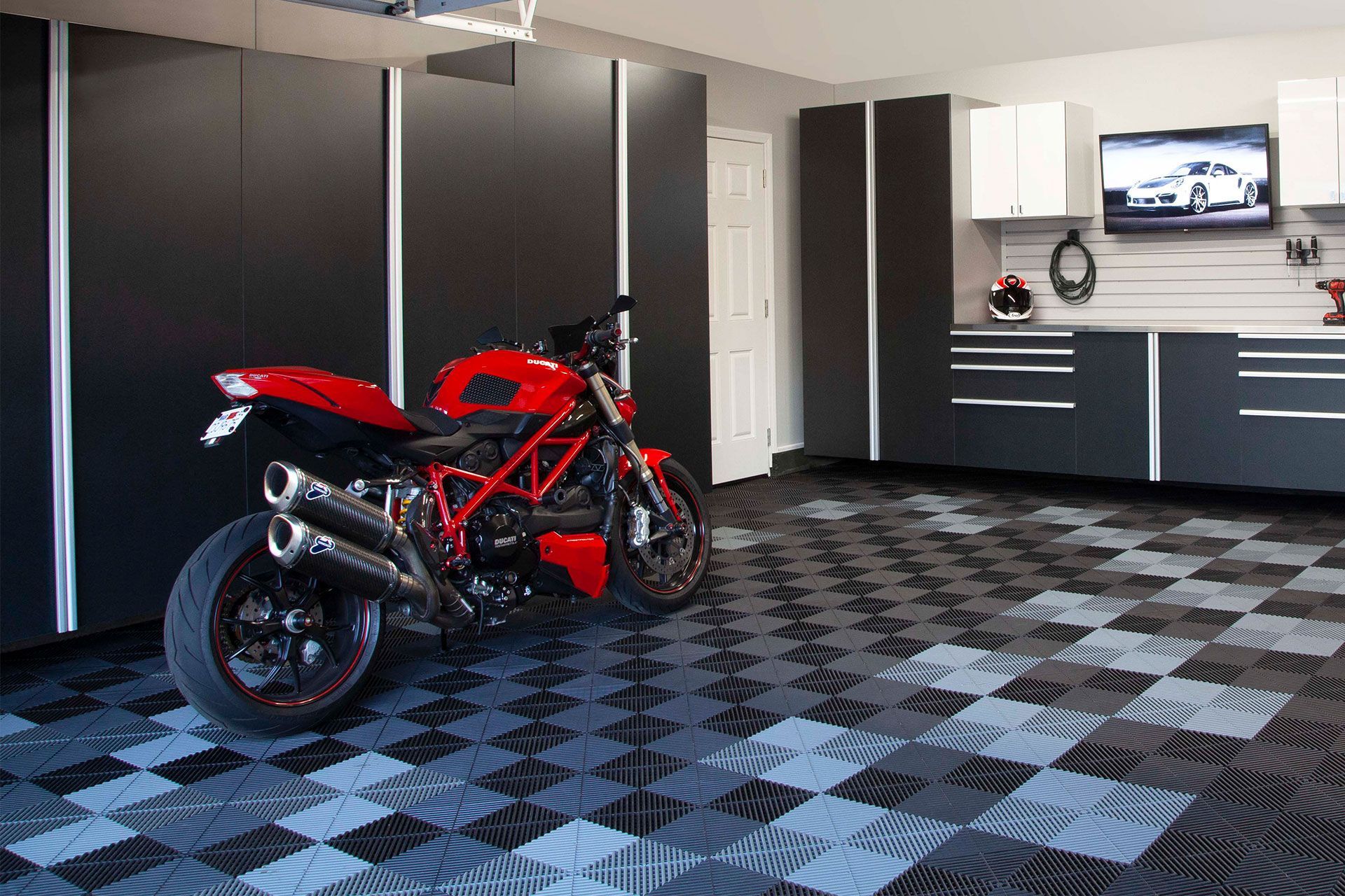 A red motorcycle is parked in a garage with a checkered floor.