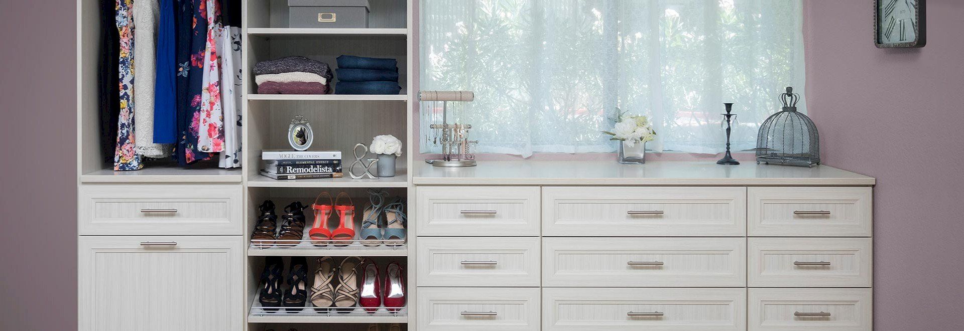 A walk in closet with lots of shelves and drawers and a window.