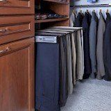 A closet filled with lots of clothes and pants hanging on racks.