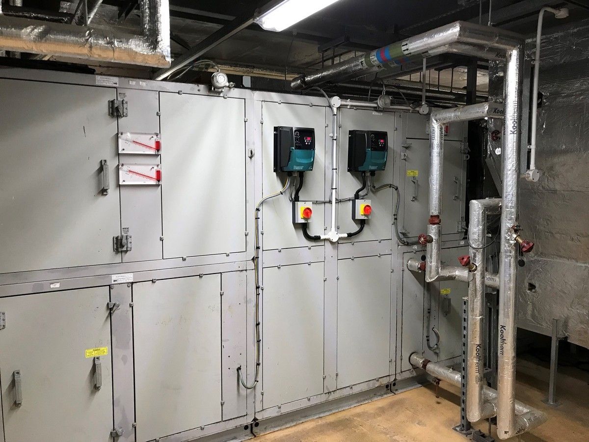 Large HVAC system with gray panels, pipes, and two black pumps.