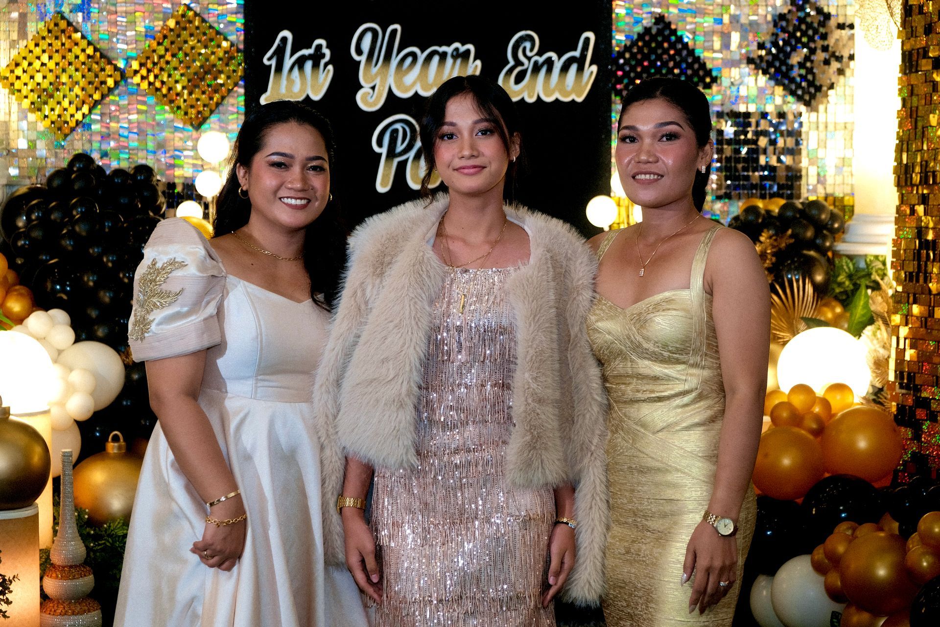 Three women pose at a party with black and gold decor