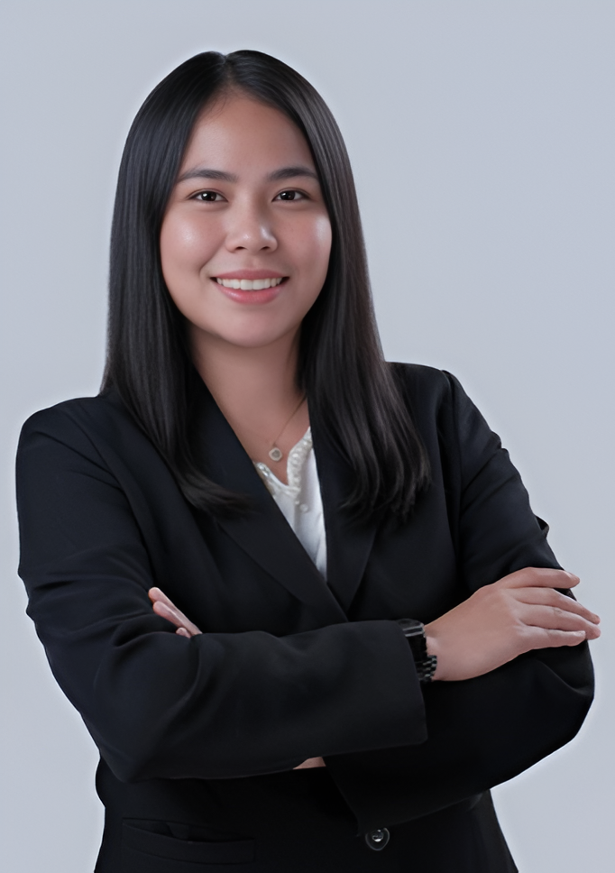 Woman with long black hair, wearing a black blazer, smiling with arms crossed against a white background.