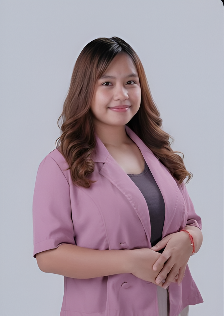 Woman with brown hair in a pink blazer and gray top, smiling against a white background.