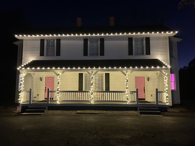 A white house with Christmas lights on the front porch