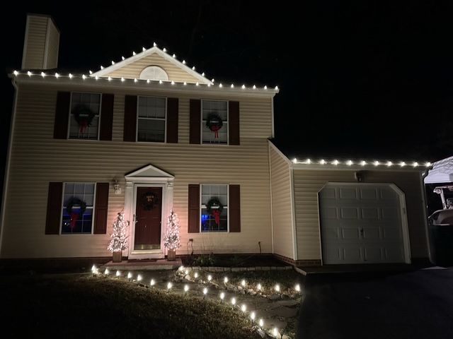 A house with Christmas lights on it is lit up at night.