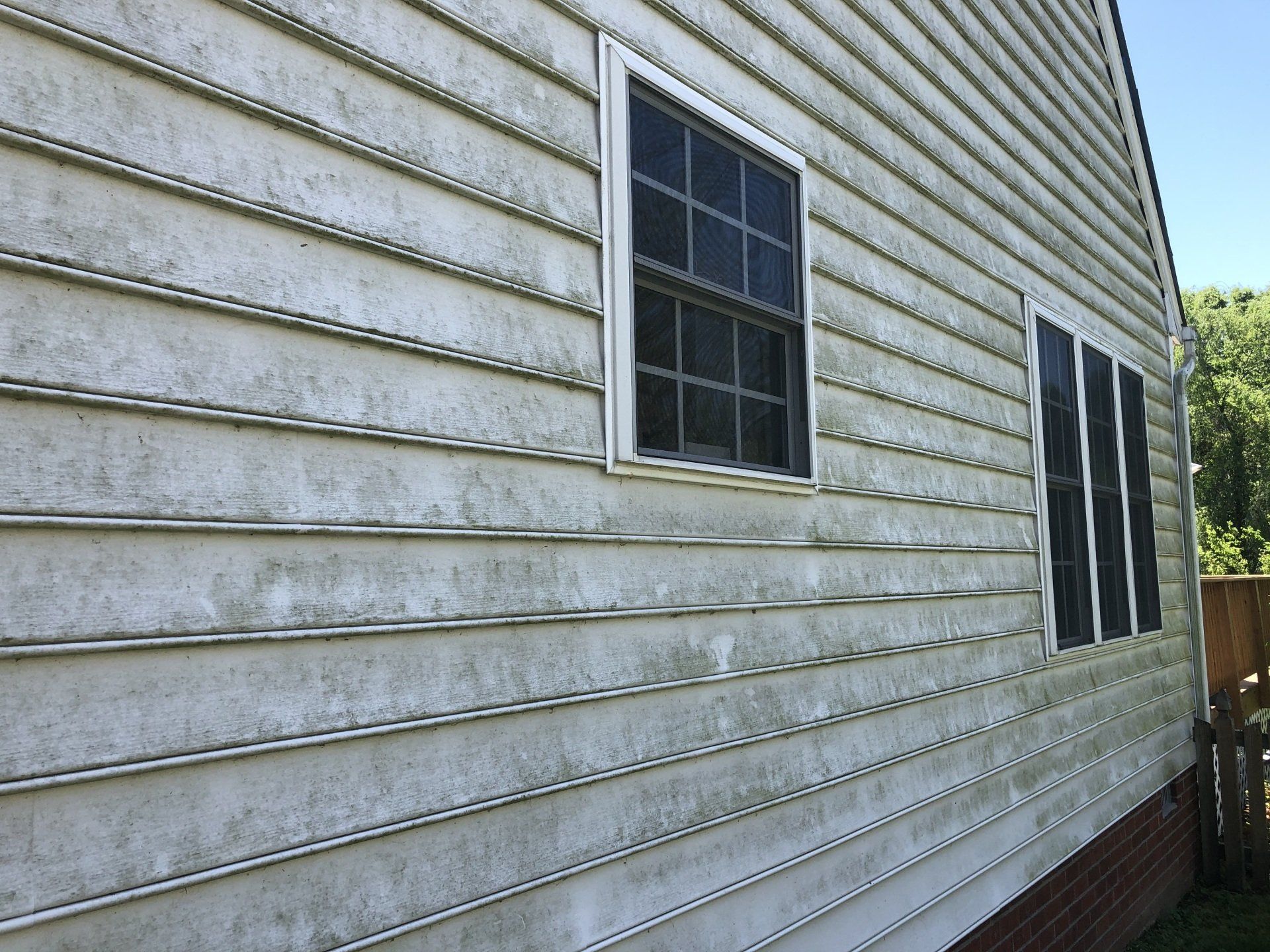 dirty white house exterior with two windows