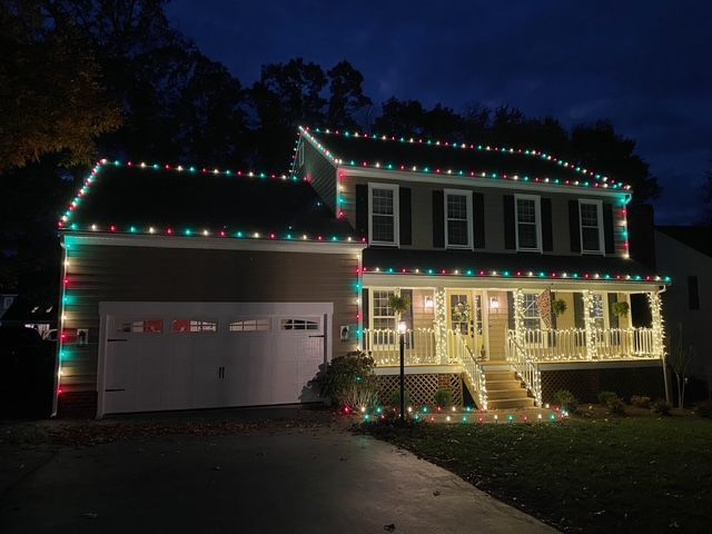 A beautiful house with Christmas lights on it is lit up at night.