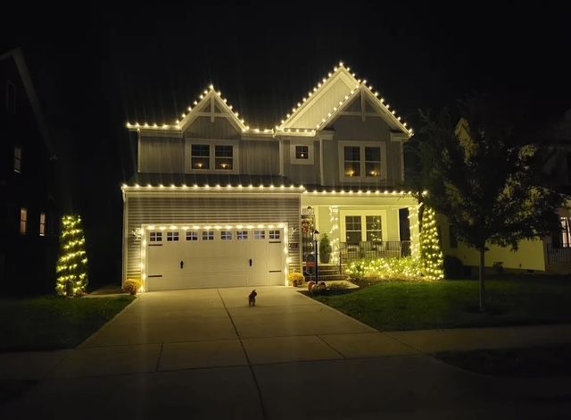 A white house with Christmas lights on it is lit up at night