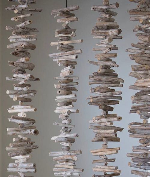 Rows of stacked driftwood pieces arranged vertically against a gray background