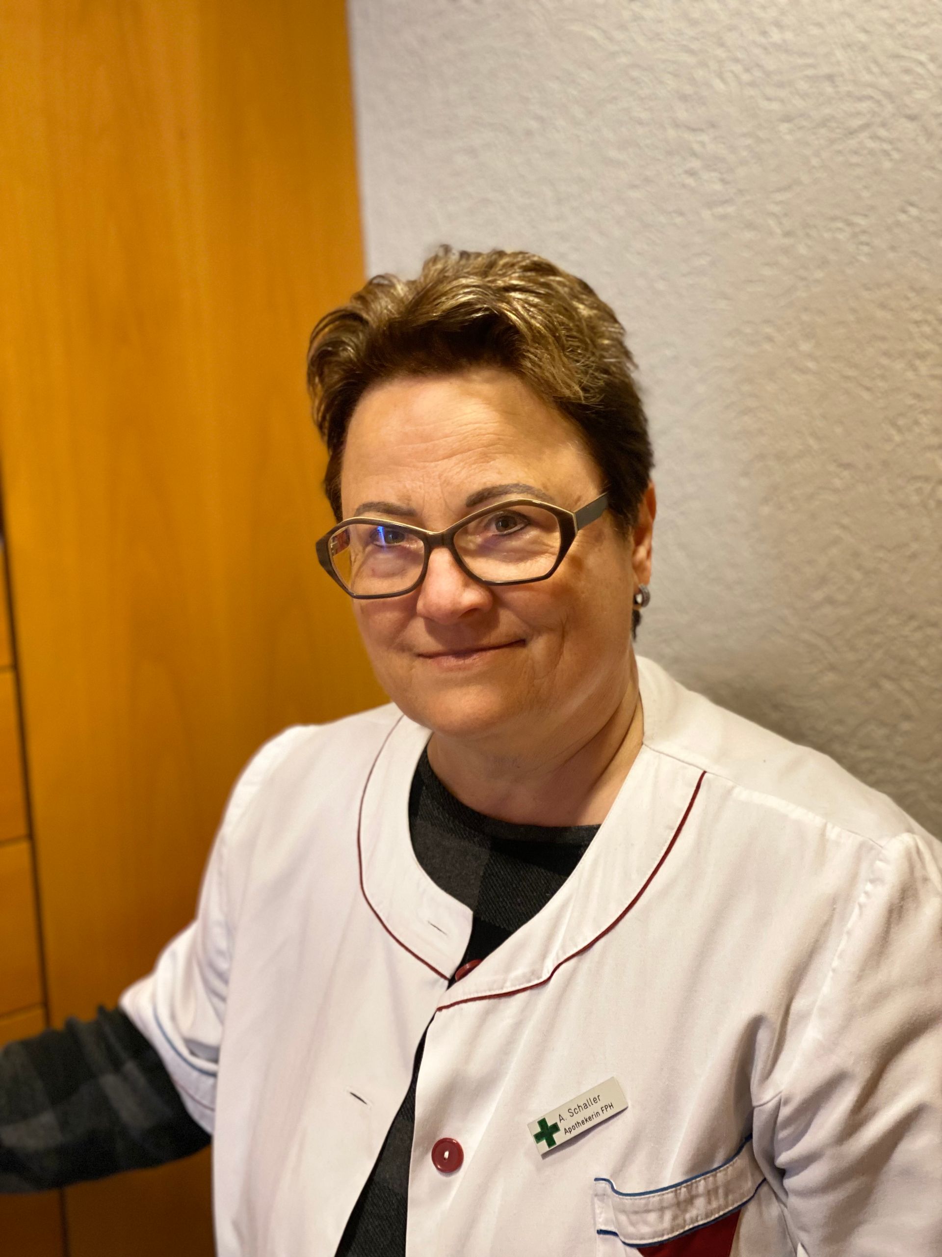 Eine Frau mit Brille und weißem Kittel lächelt in die Kamera.