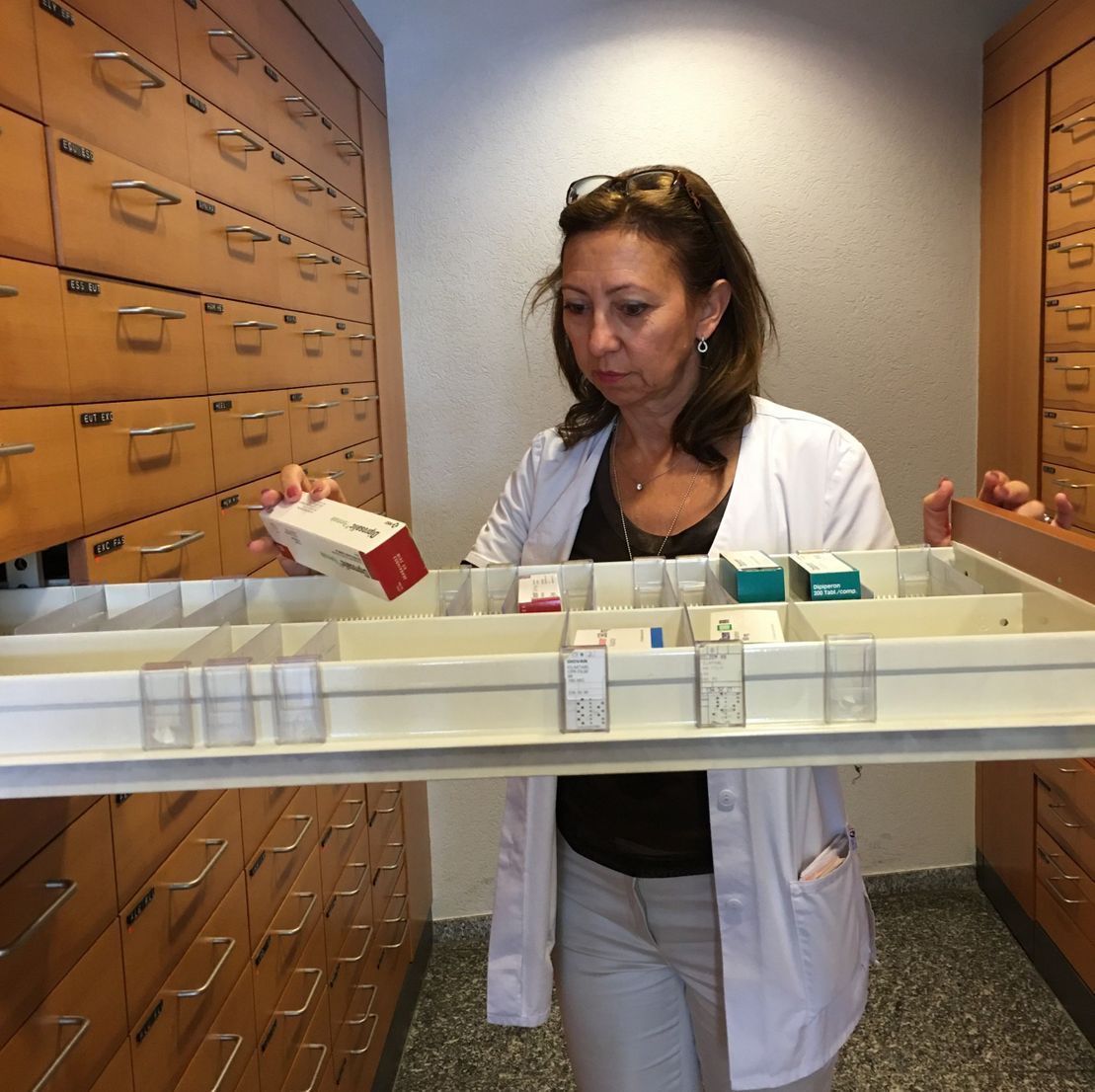 Eine Frau im weißen Kittel hält ein Tablett mit Pillen