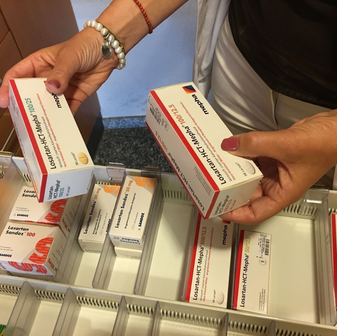 Eine Frau hält eine Schachtel mit der Aufschrift „Losartan“