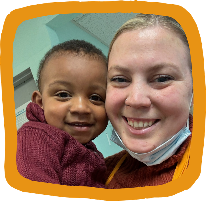 a woman wearing a face mask holds a child in her arms