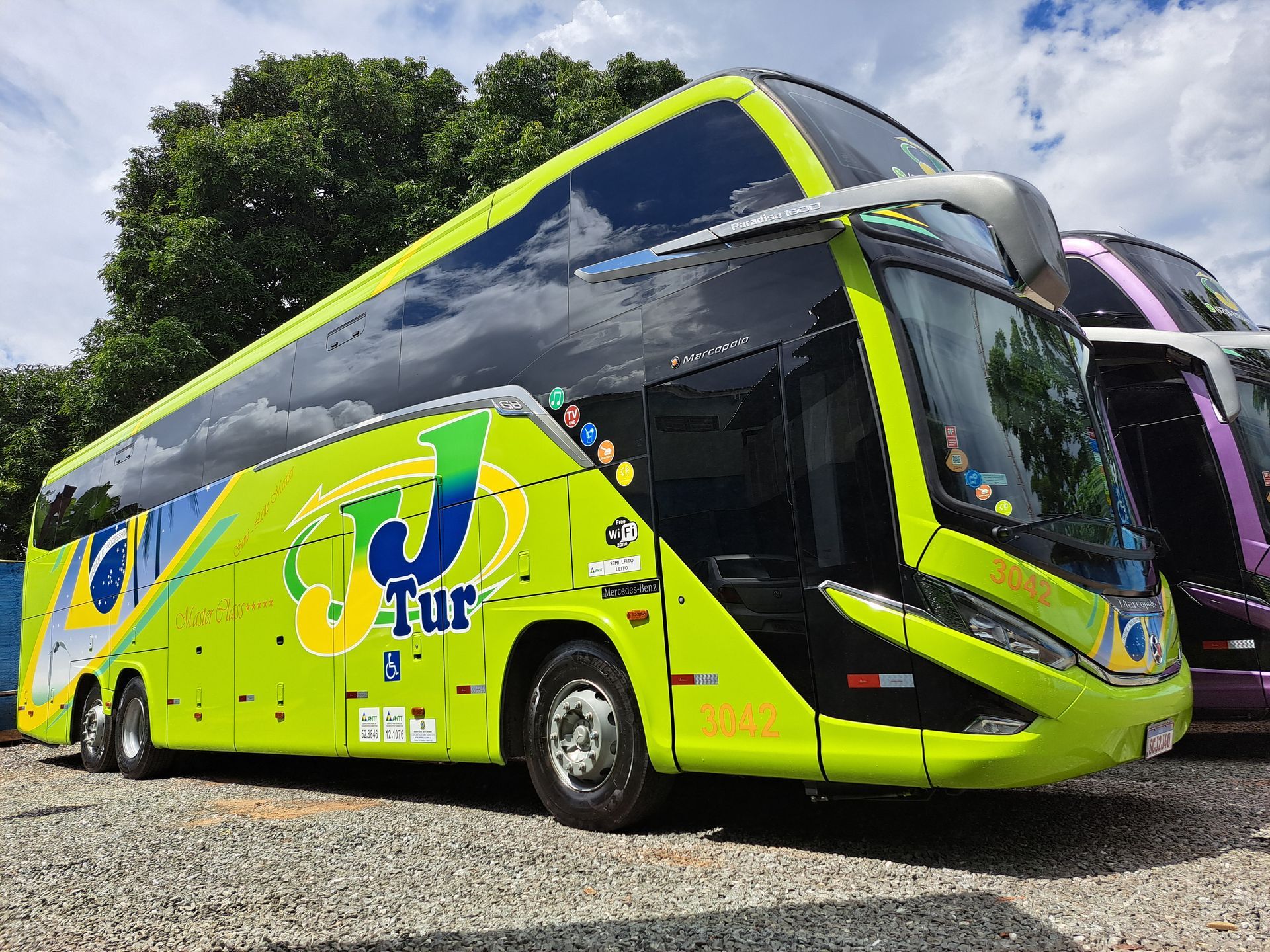 Um ônibus de dois andares verde limão com o logotipo da JJTur, estacionado ao ar livre.