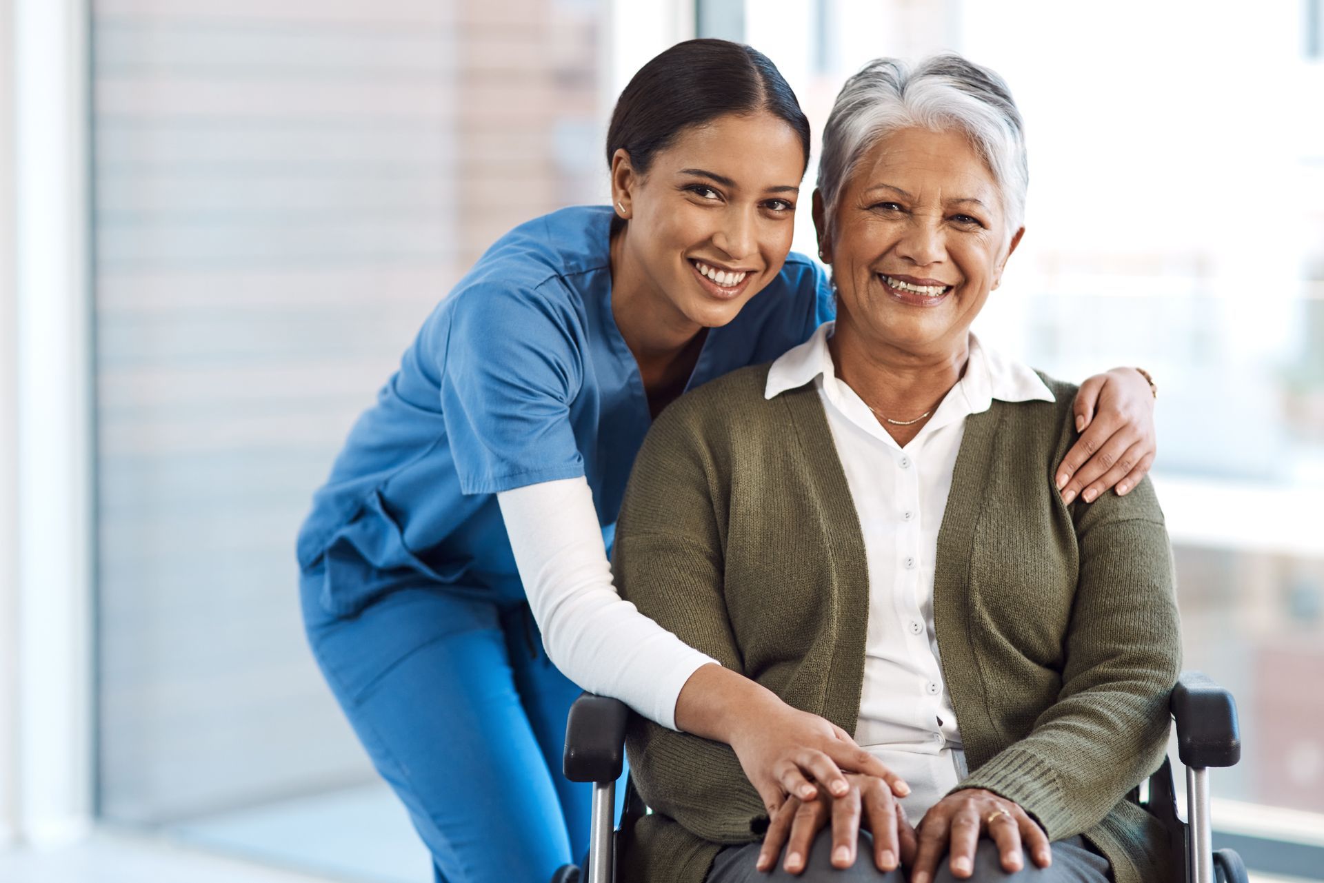 A nurse is standing next to an elderly woman in a wheelchair.