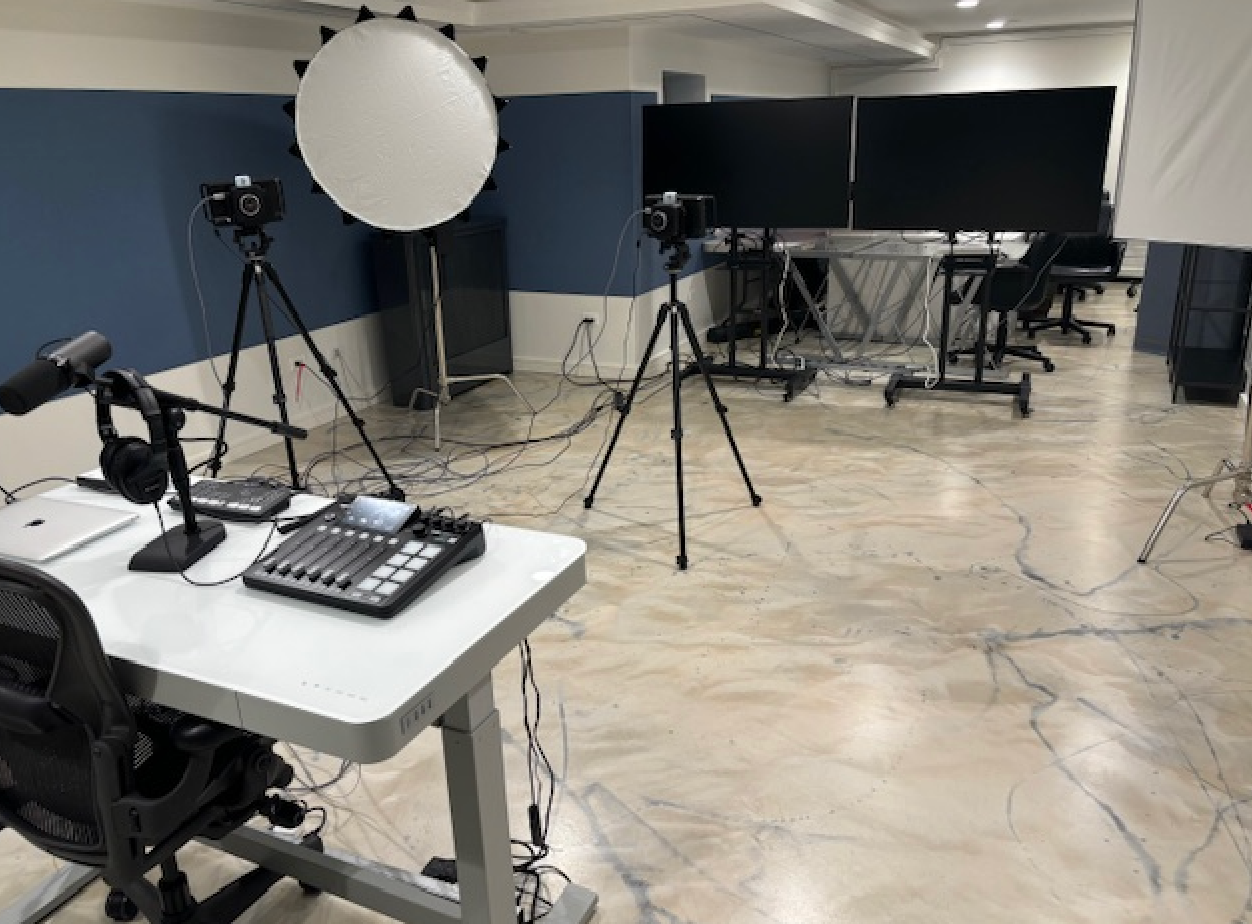 A room with a table , chairs , a microphone and a mixer.