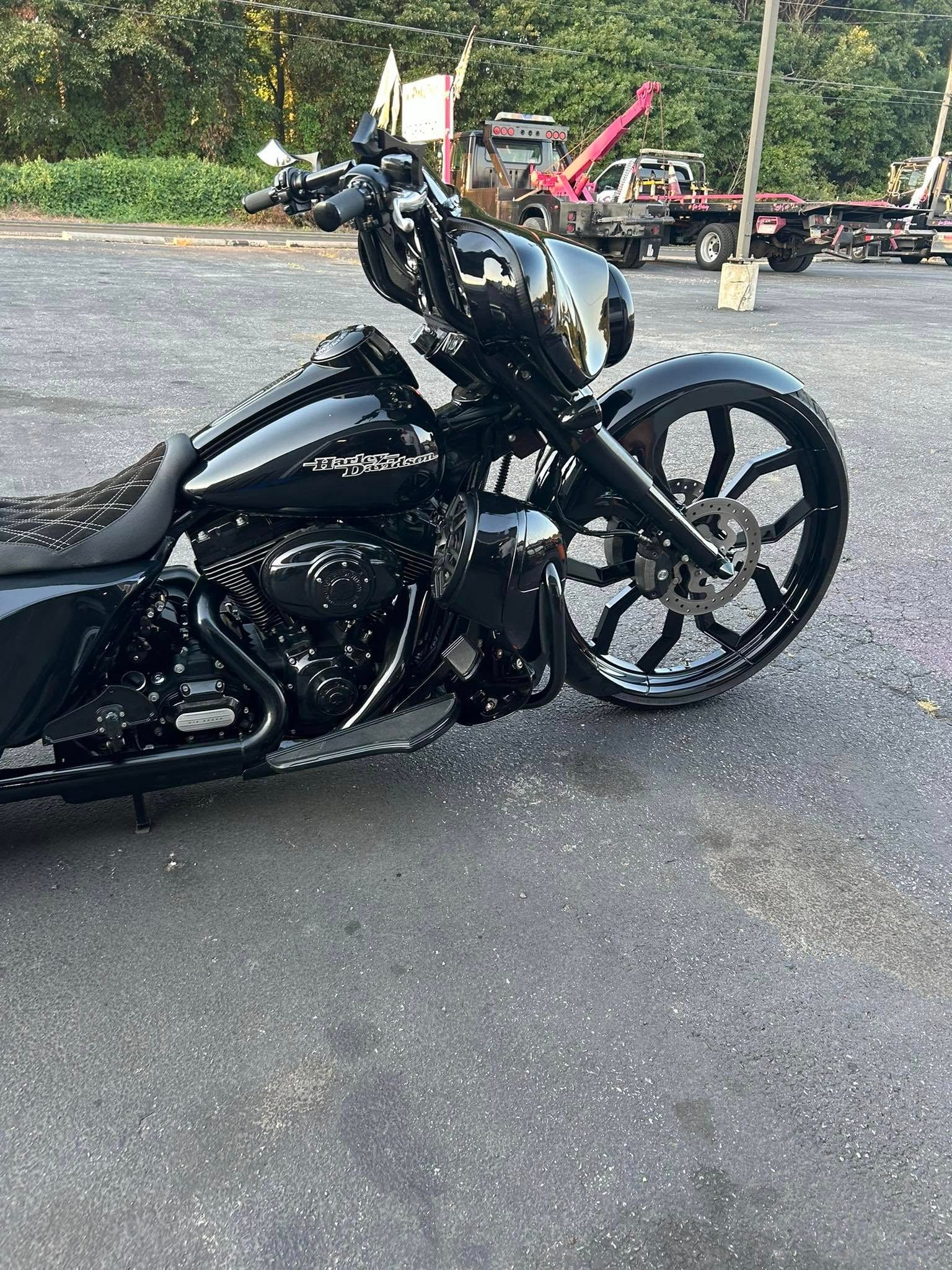 Black custom motorcycle with large front wheel parked outdoors.
