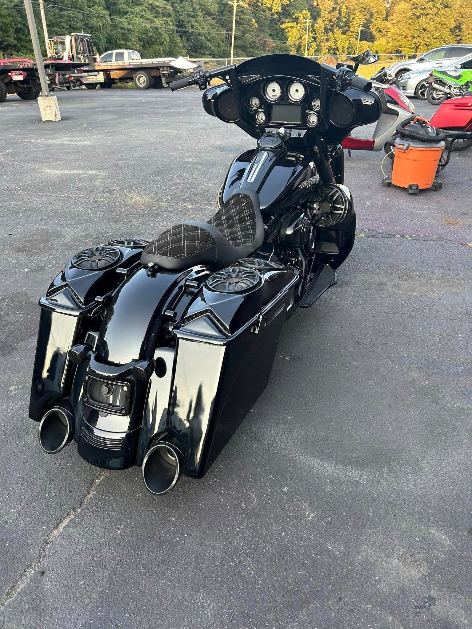 Black custom motorcycle parked on asphalt with chrome exhaust pipes and saddlebags.