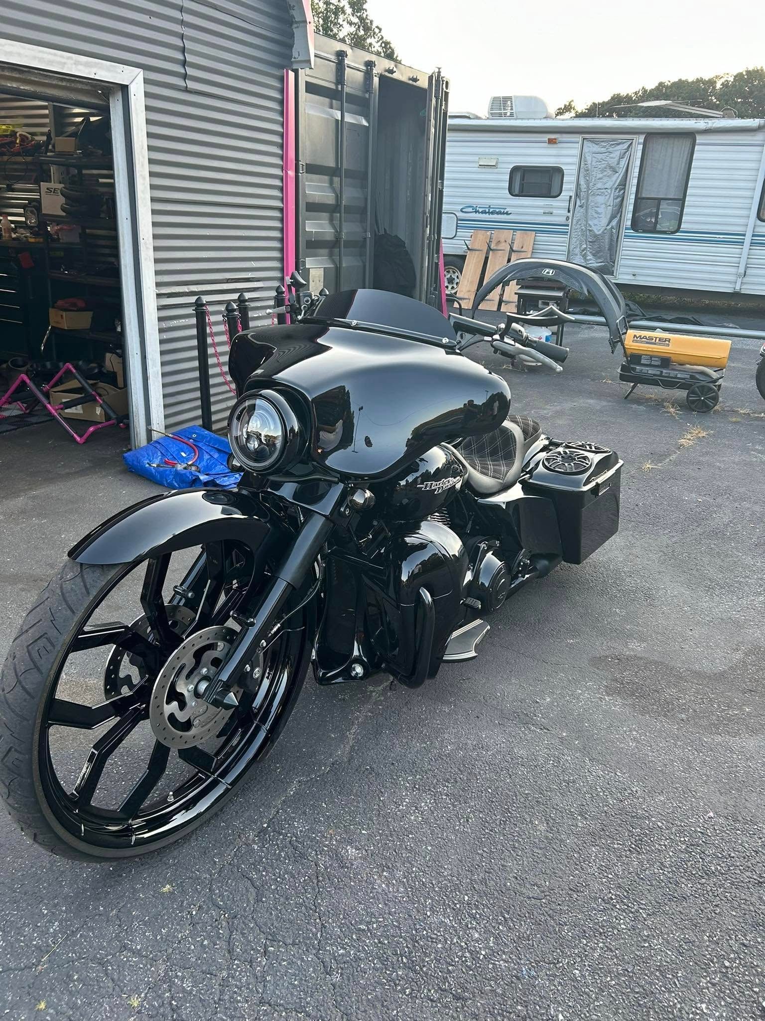 Black custom motorcycle parked outside a shop, with a large front wheel and a fairing.