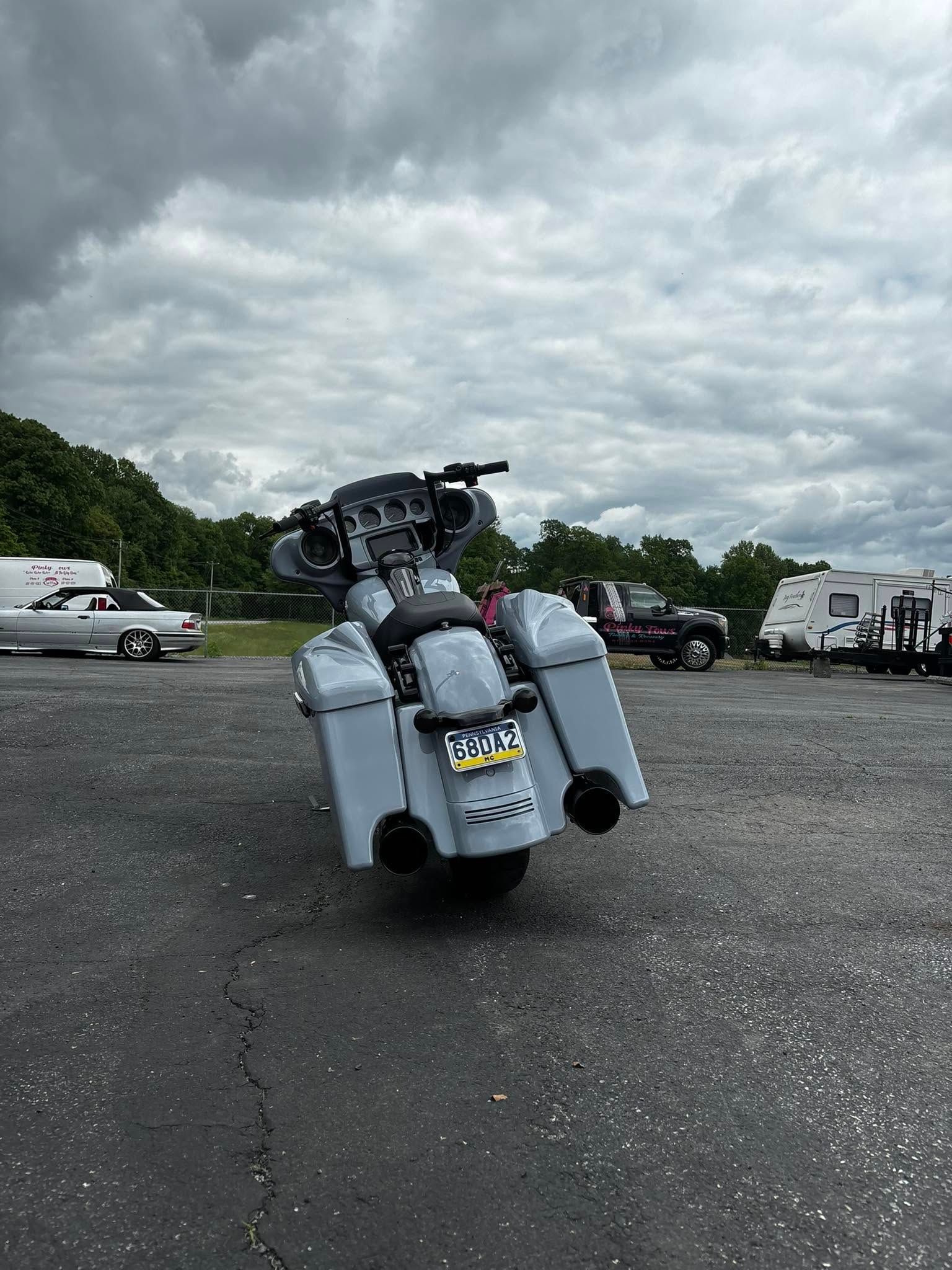 Gray motorcycle with large saddlebags, parked outdoors on asphalt, overcast sky.