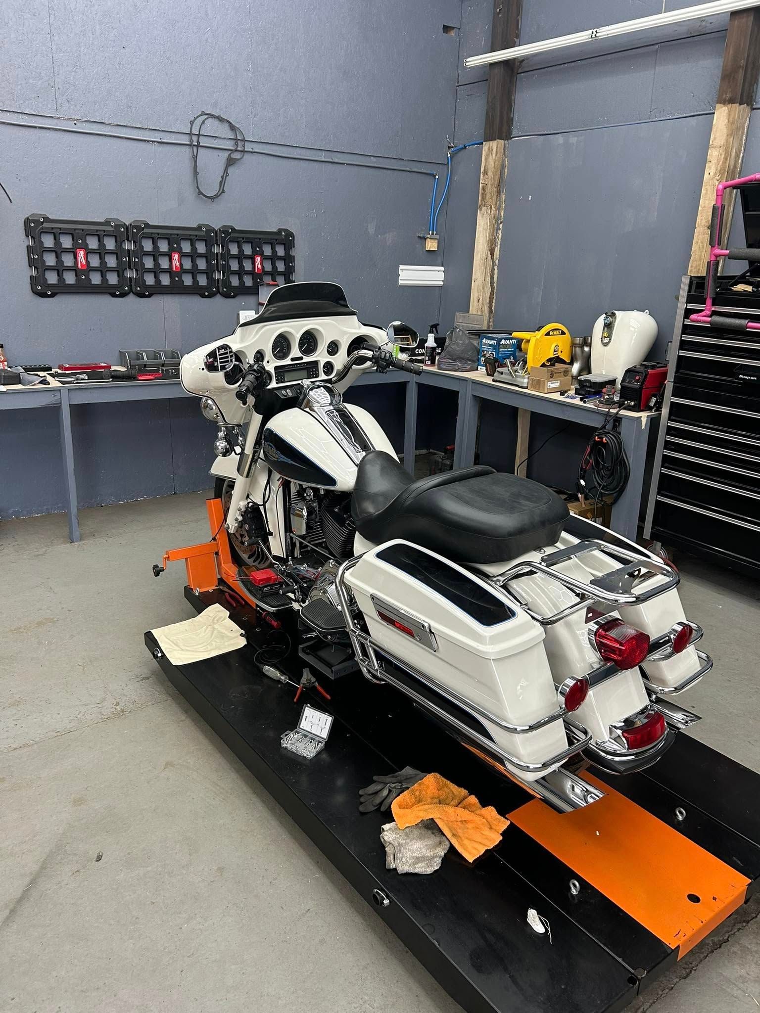 A white and black Harley Davidson motorcycle on a lift in a garage setting.