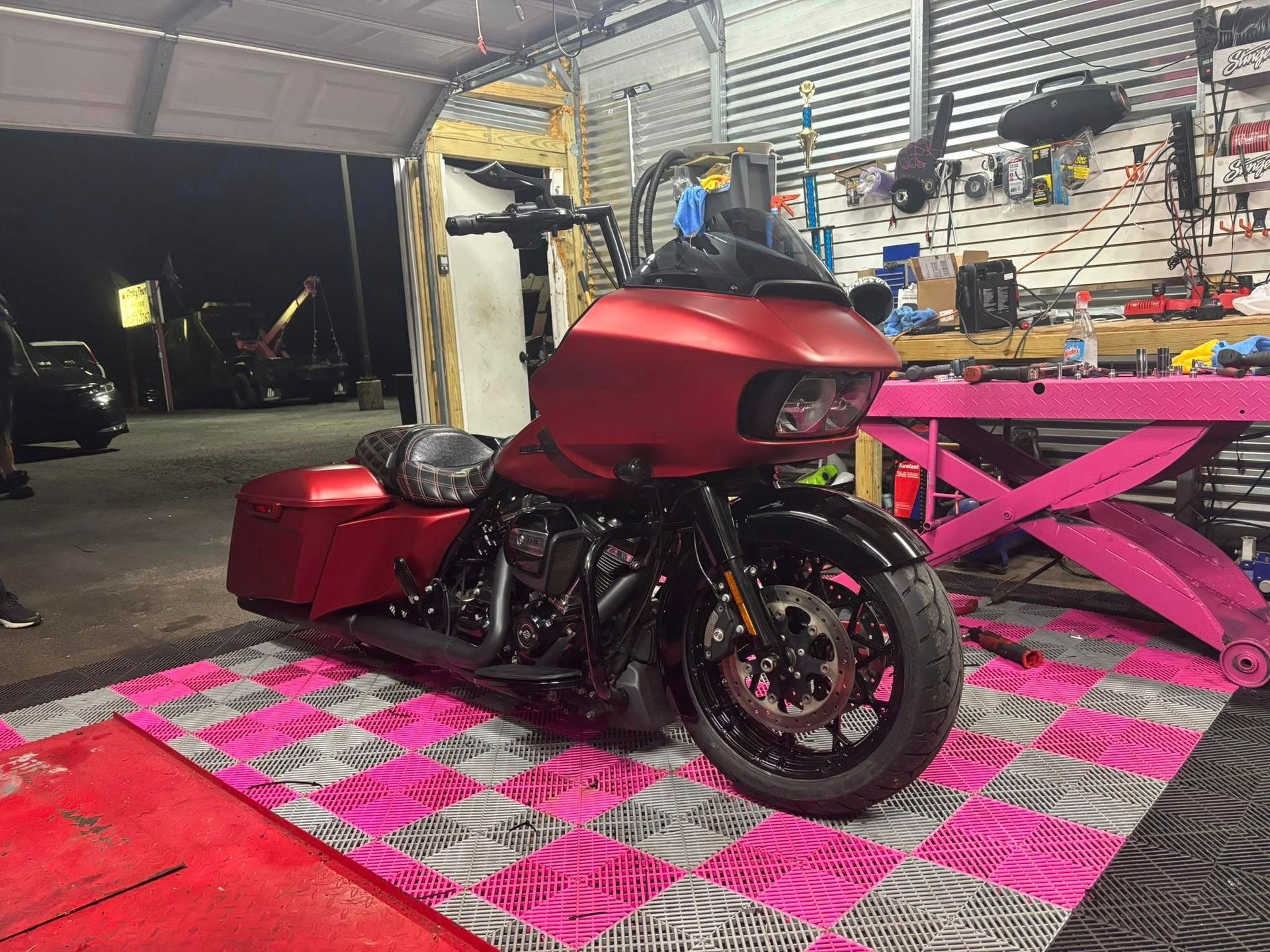 Red Harley-Davidson motorcycle on a pink and gray checkered floor in a garage.