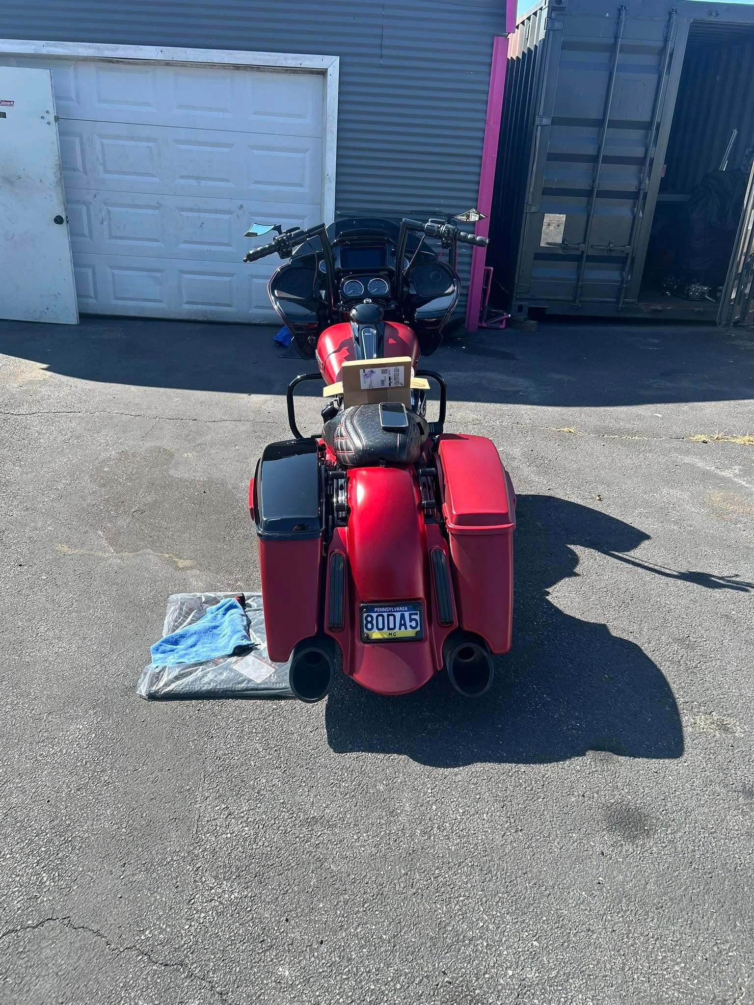 Red motorcycle parked on pavement in front of a building.