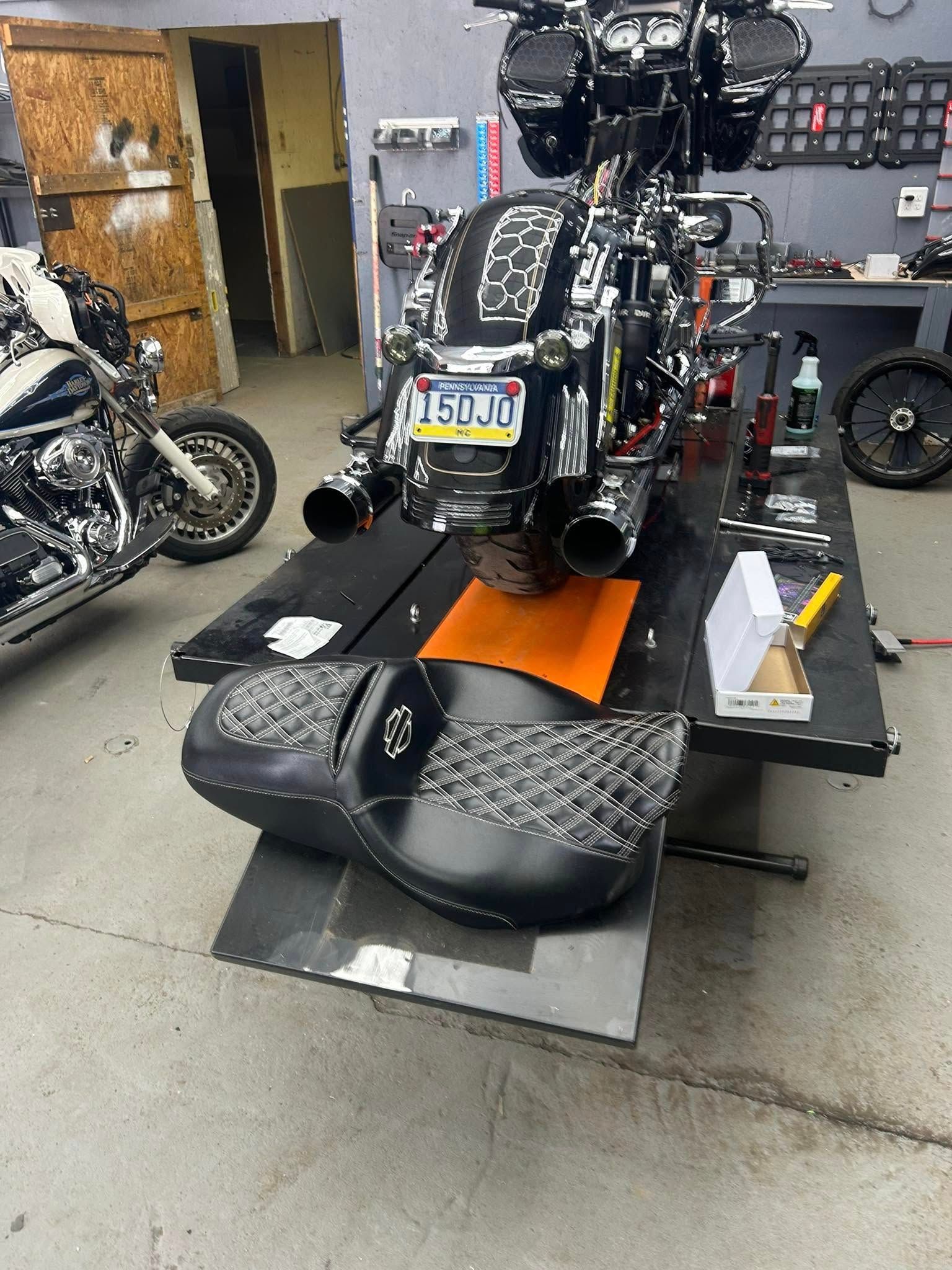 Motorcycle on a lift with a detached black seat, in a repair shop.