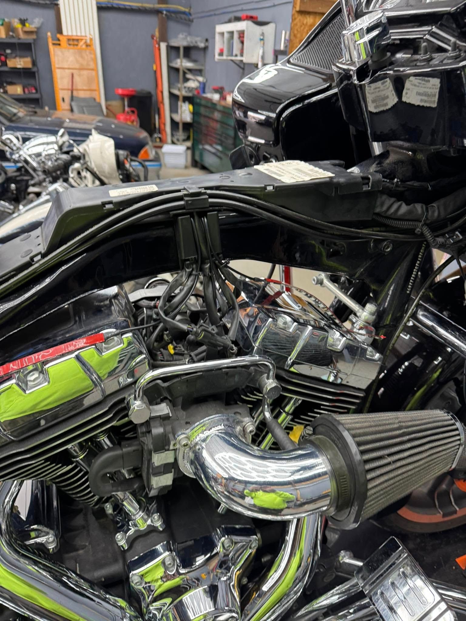 Black motorcycle engine with chrome and a silver air filter in a workshop.