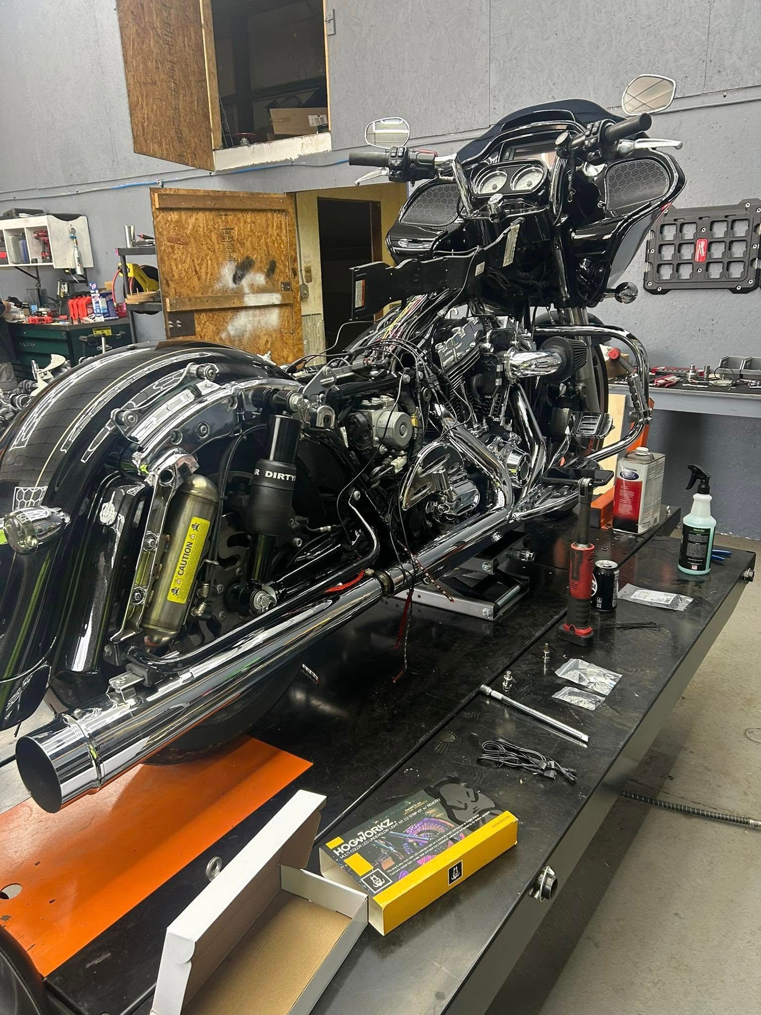 Black motorcycle in a shop, on a lift. Tools and parts are scattered around.