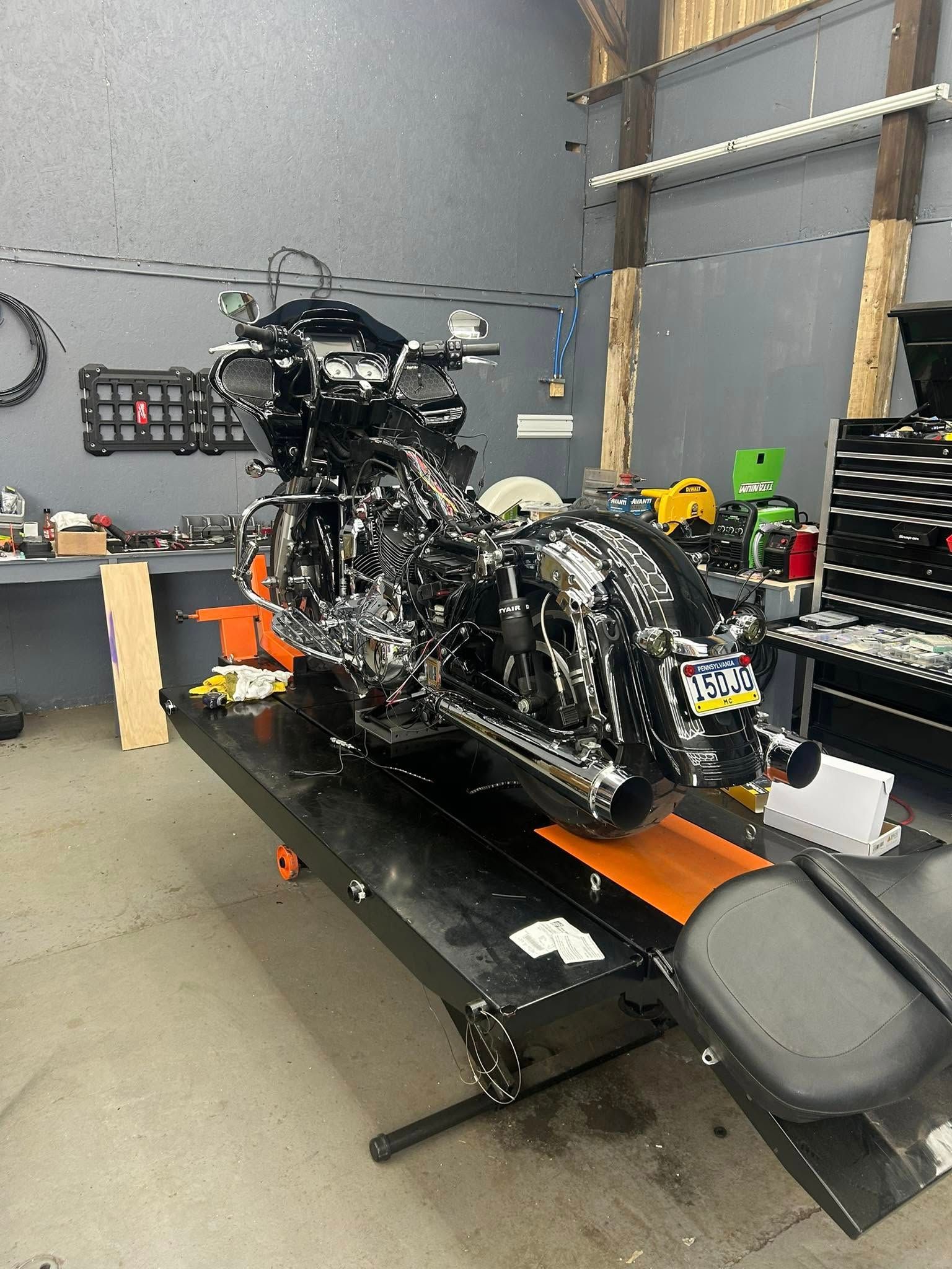 Black motorcycle on a lift in a garage, tools and equipment visible.