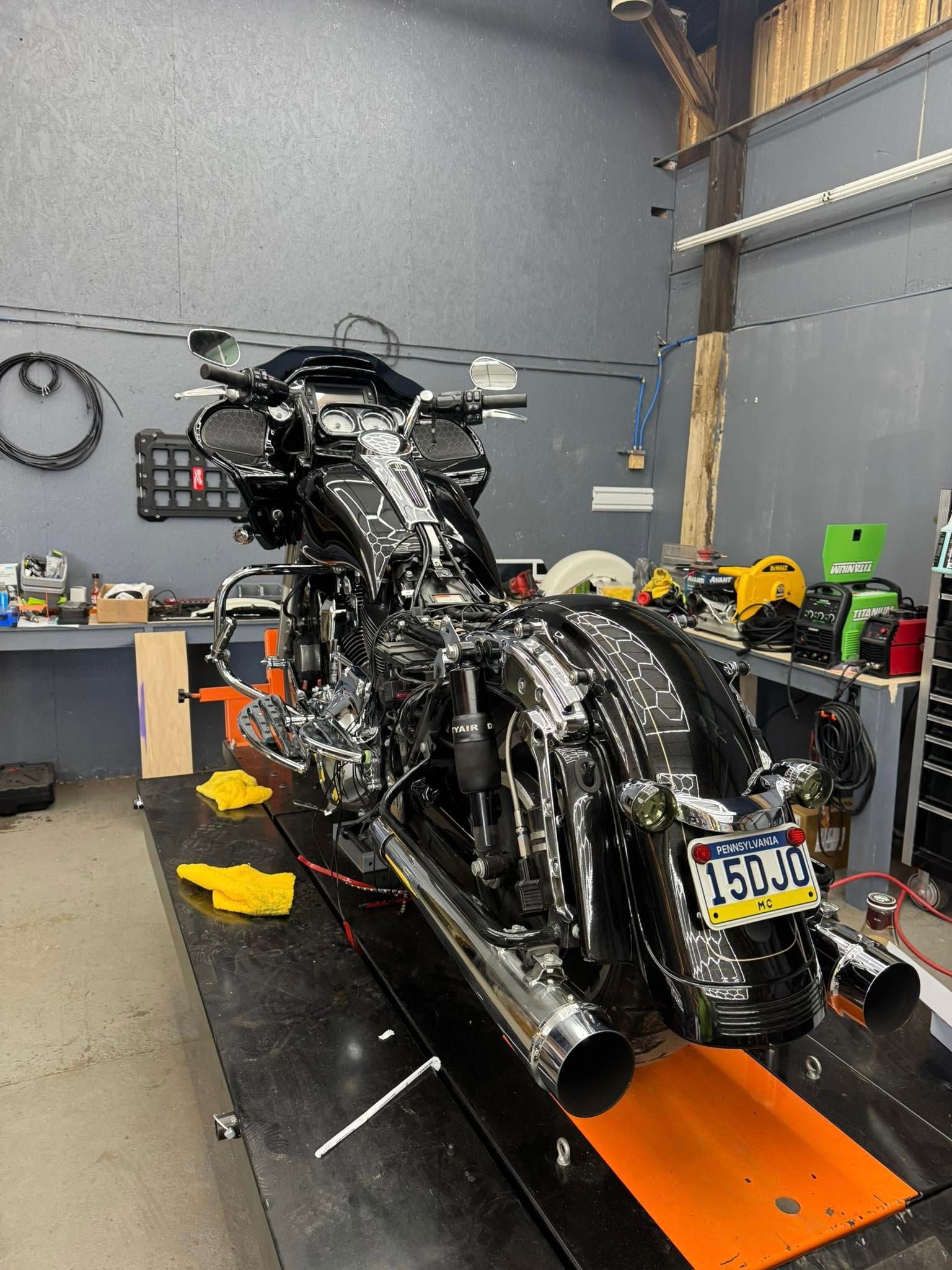 Black Harley-Davidson motorcycle on a lift in a garage, shiny chrome exhaust, New Jersey license plate.