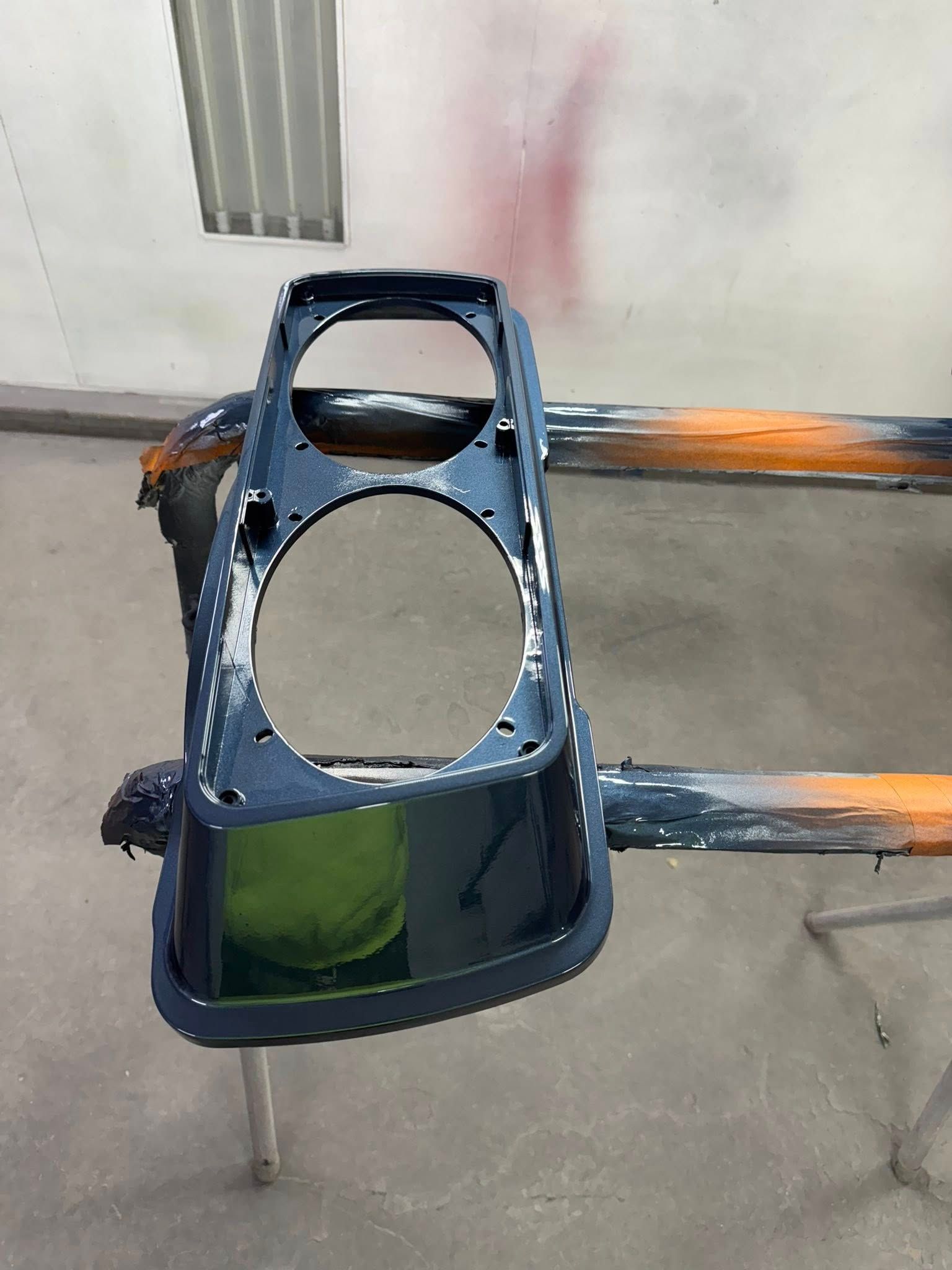 Dark blue painted dashboard component in a paint booth.