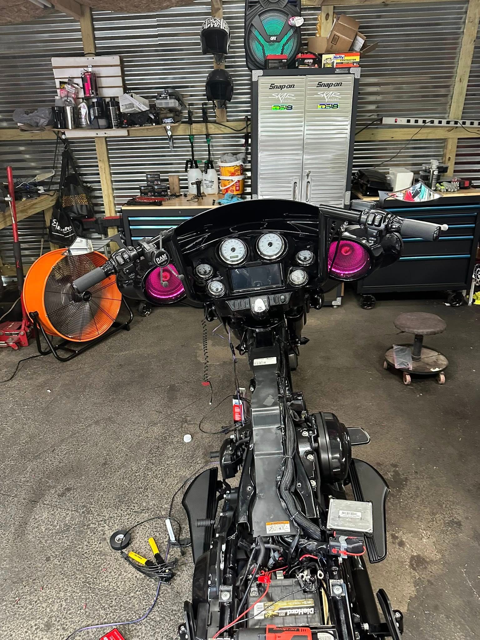 Motorcycle undergoing repair in a garage. Black frame, purple accents. Tools and parts are scattered around.