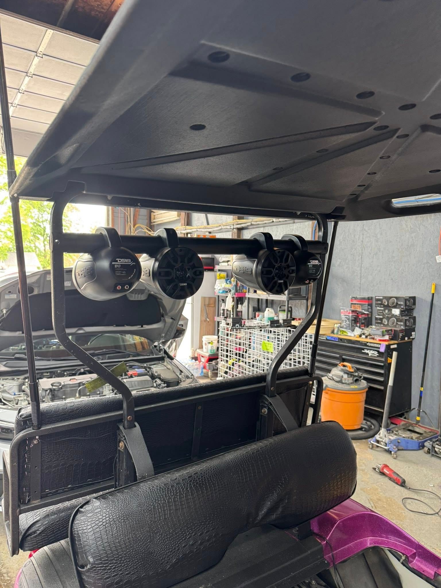 Black golf cart with mounted speakers in a garage setting.