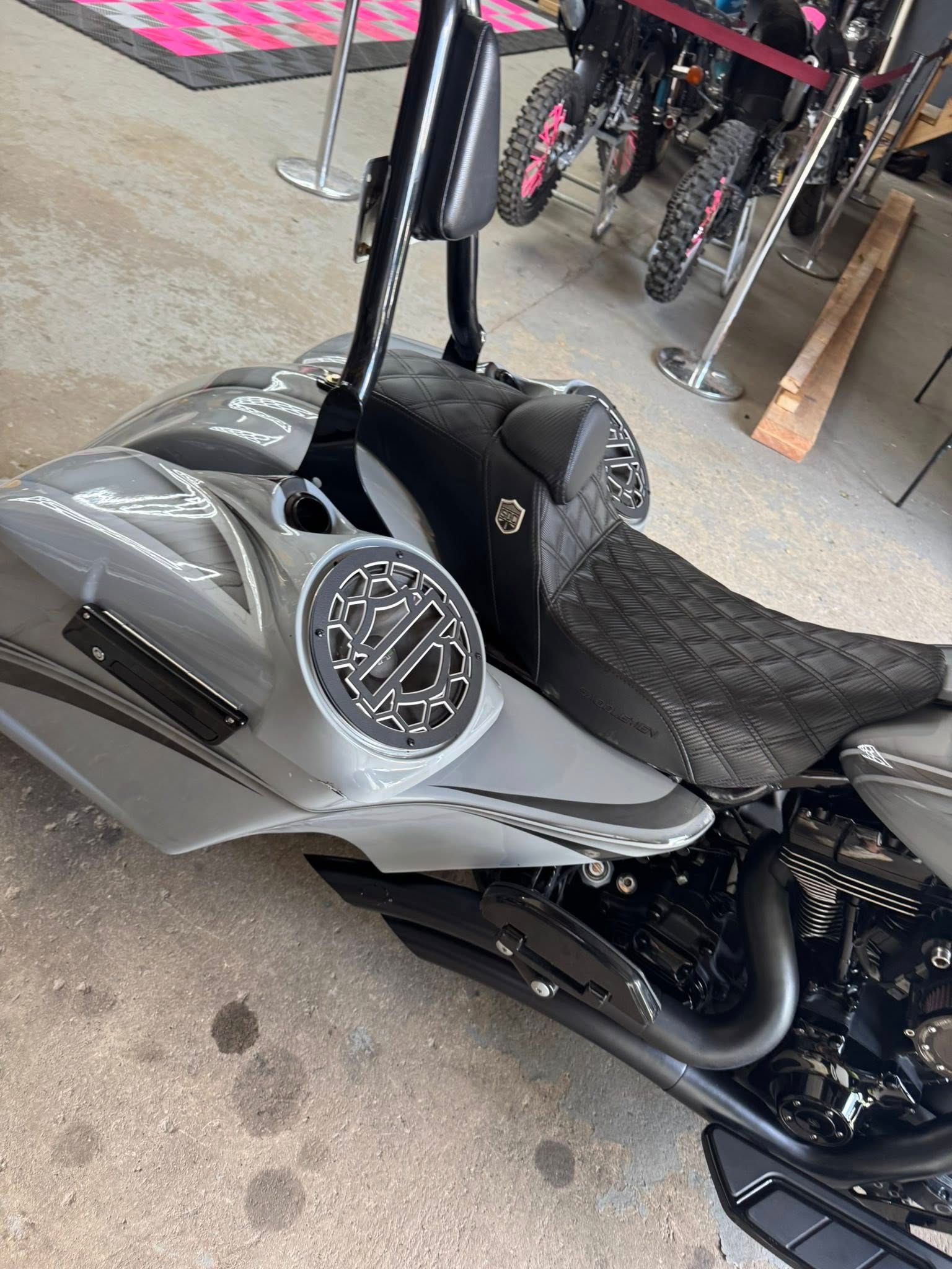 Gray custom motorcycle with a textured black seat, indoors.