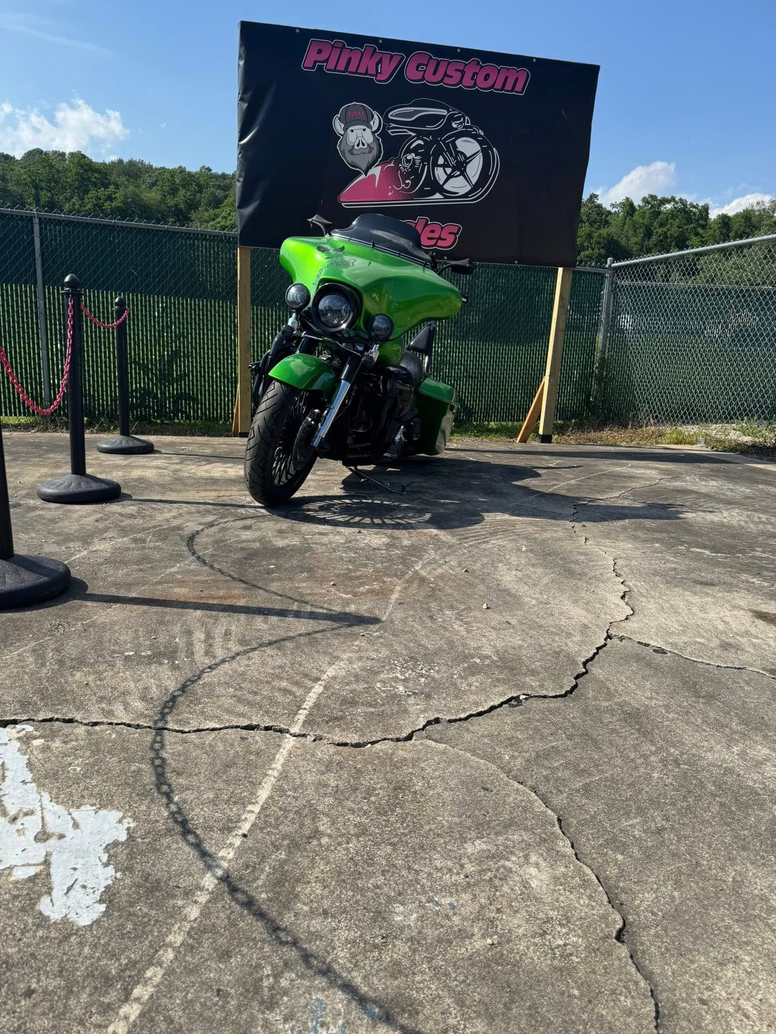 Green motorcycle parked near a sign that reads 