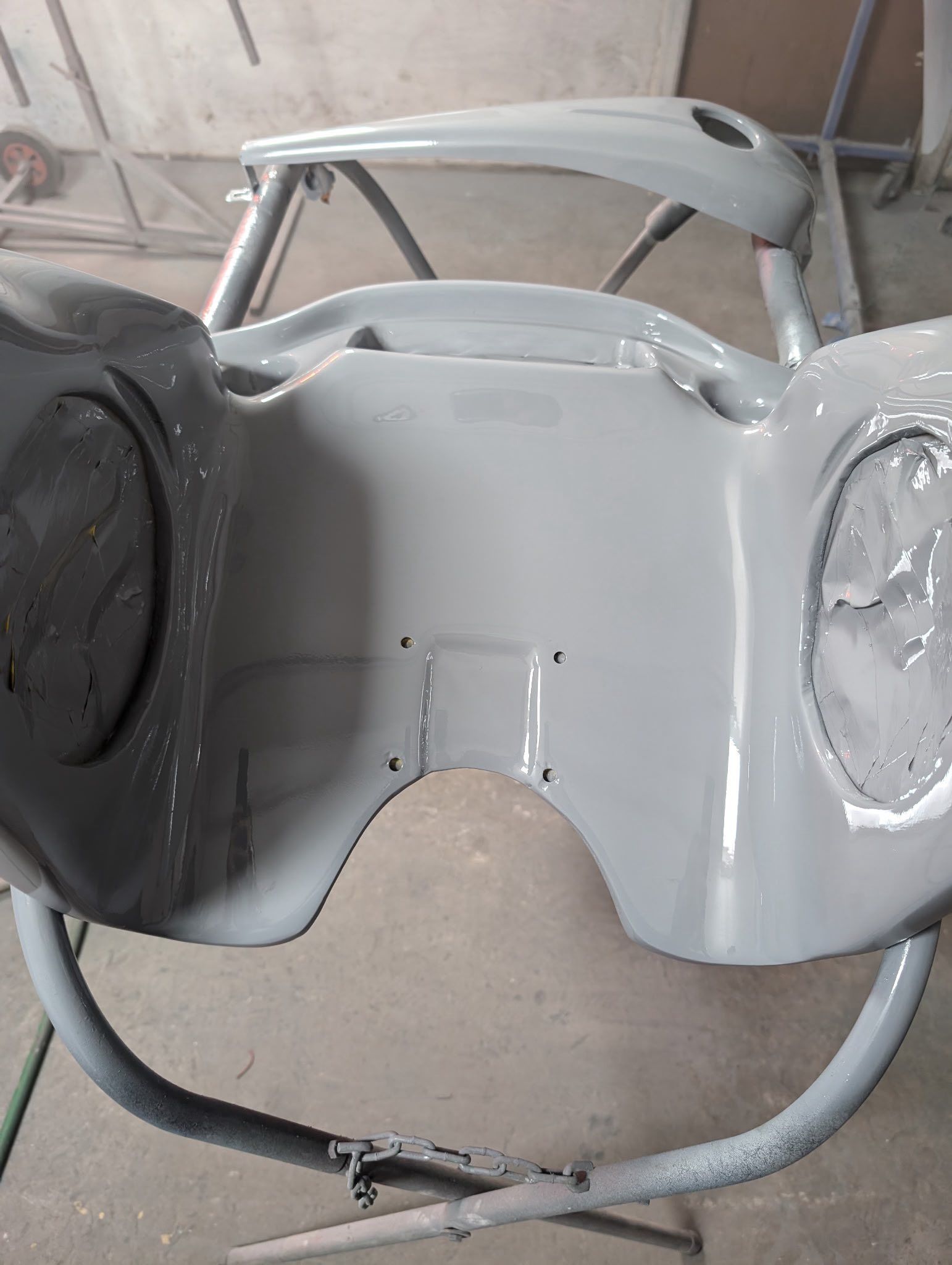 Gray motorcycle gas tank on a stand, freshly painted.