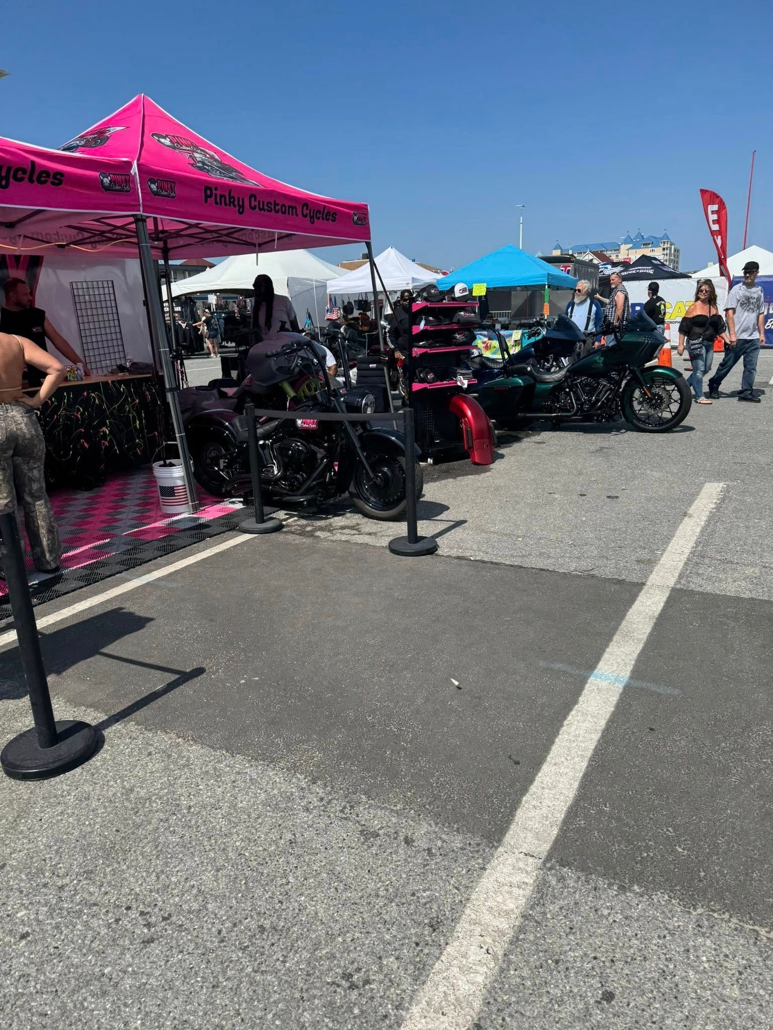 Motorcycle event: Black motorcycles displayed next to a pink tent on a sunny day.
