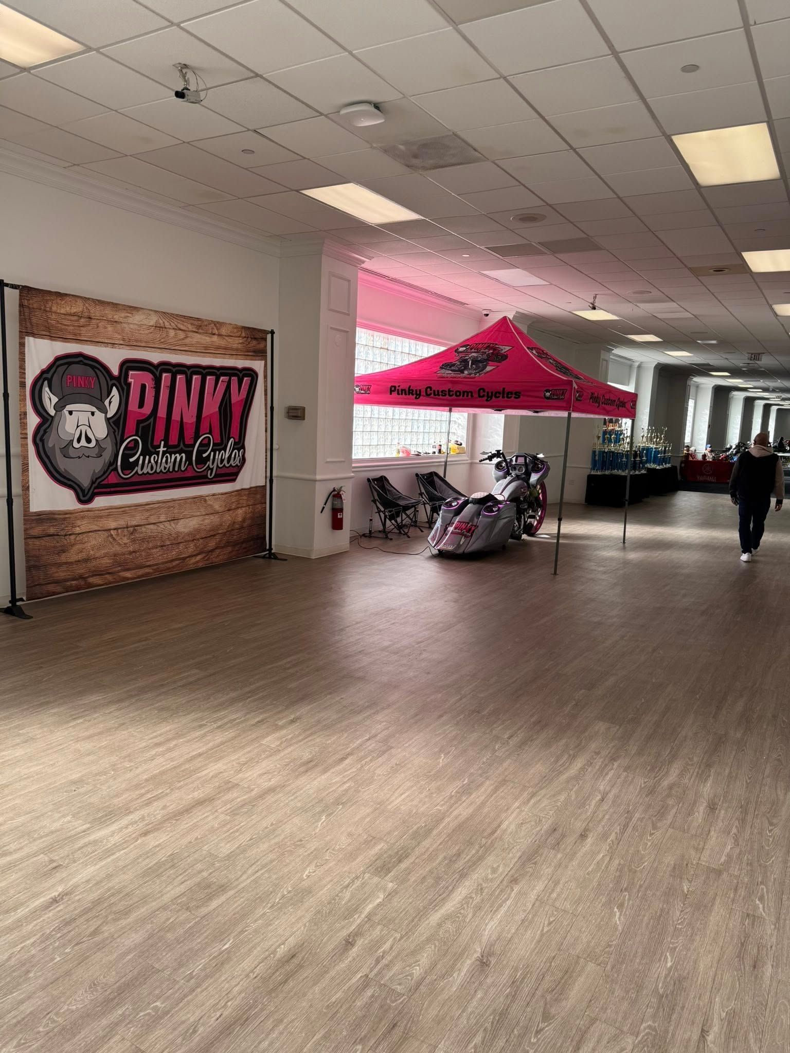 Interior shot of a vendor area. Displays include a pink tent, motorcycle, and banner with the word 